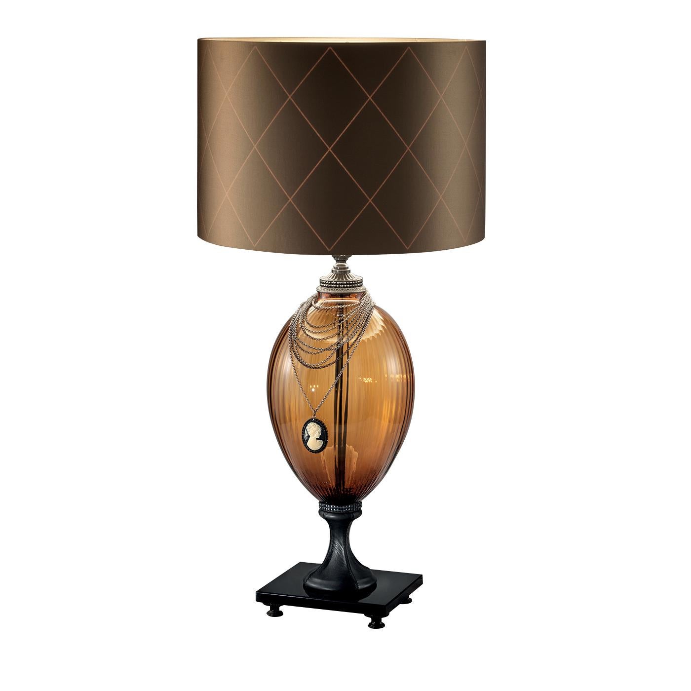 This truly stunning lighting piece is perfectly paired with a modern interior. The amber glass body with its ridged finish sits atop a black leather flared foot and is accented with a handmade, 24-karat gold-plated necklace with a cameo. The