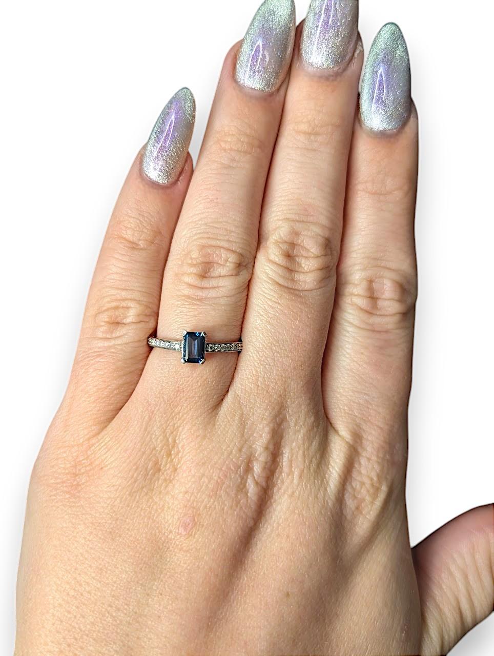 La bague Audrey est une pièce raffinée et sophistiquée, mettant en vedette une topaze bleue de Londres de 0,50 ct de couleur riche, taillée en émeraude et sertie dans de l'or blanc poli 10K, accentuée par 0,17 ctw de diamants ronds naturels