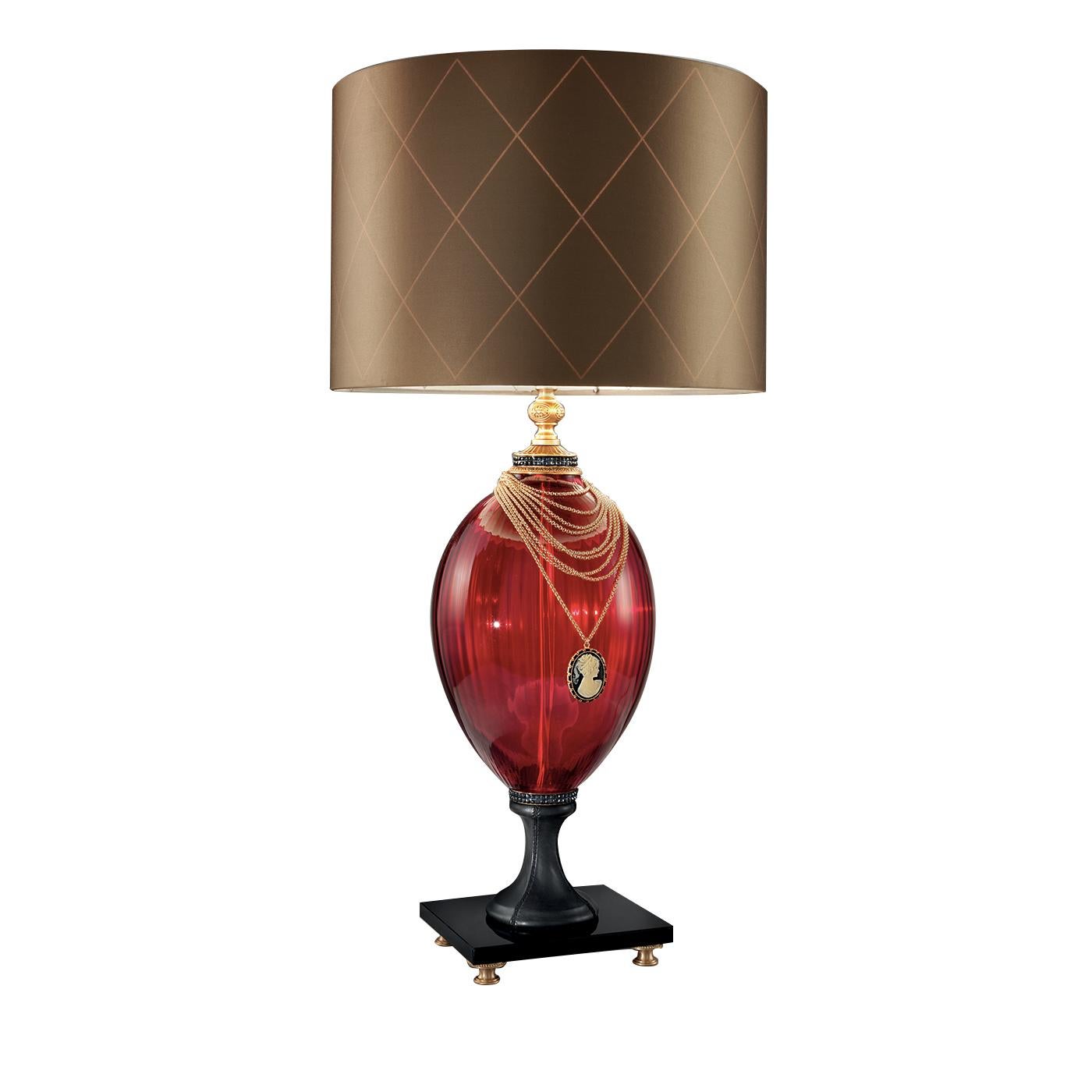 Blending timeless style with a vintage charm, this stunning lamp is a true masterpiece. This elegant lamp sports a silhouette with a ruby glass body and a dazzling 24-karat gold-plated decorative necklace with cameo. The square marble base with