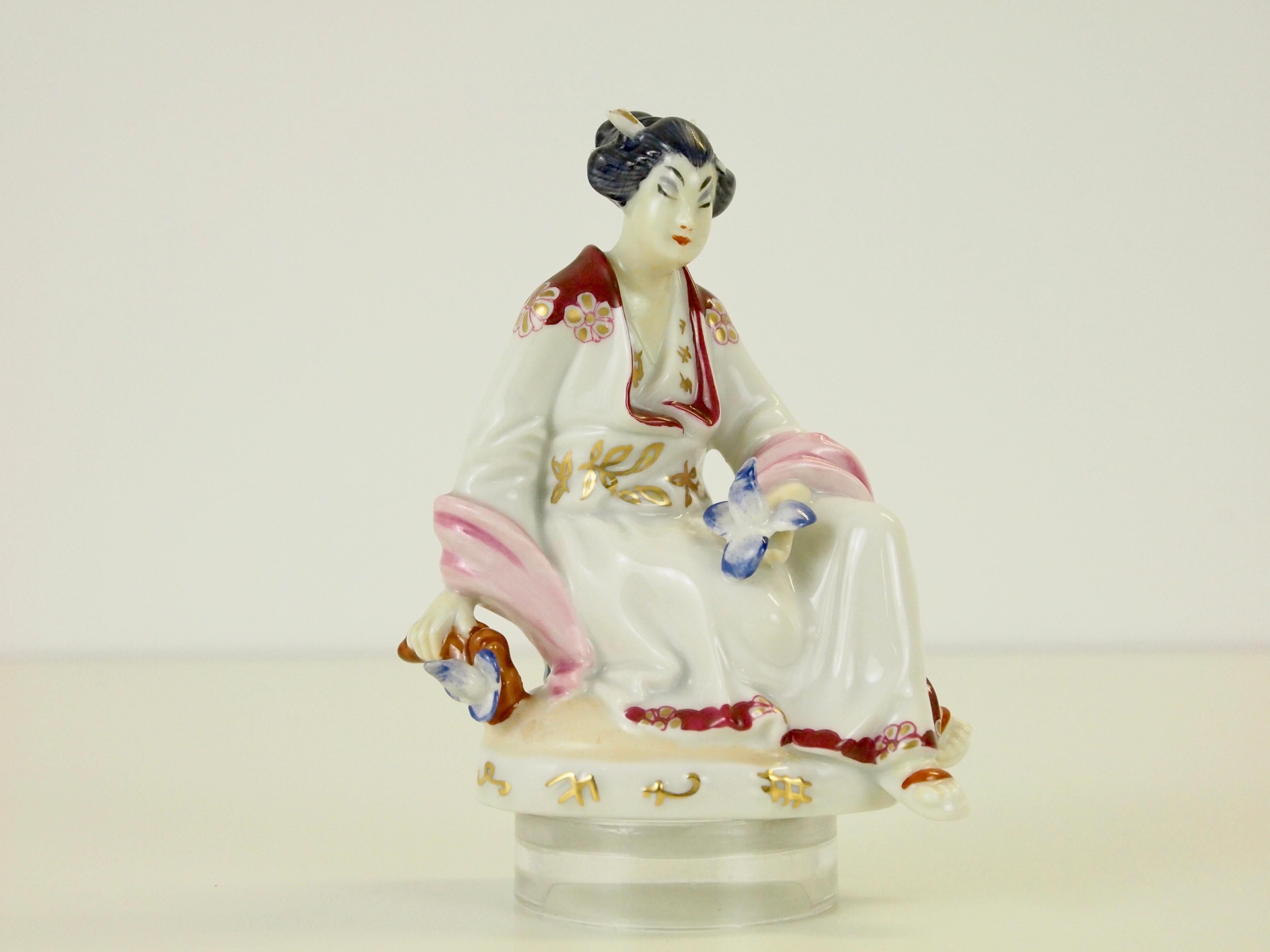 Delicate fine porcelain figurine depicting a Chinese woman.

This figurine was (like the other figurine depicting a Chinese man playing the flute) designed in 1926 by Mathilde Szendrö-Jaksch for Augarten Wien (Vienna). It is very well handcrafted