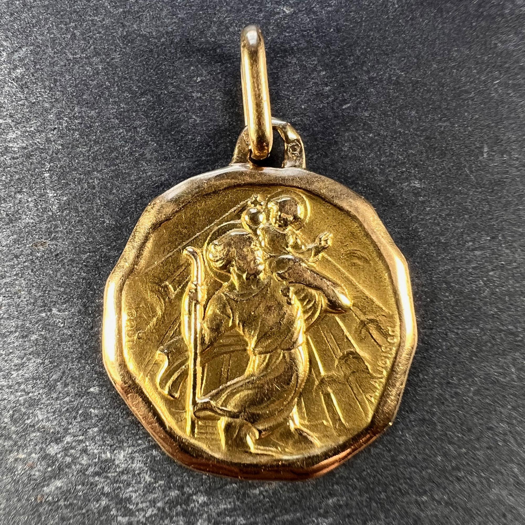 A French 18 karat (18K) yellow gold charm pendant or medal designed by Grun for Augis depicting St Christopher carrying the infant Christ across the river. Stamped with the eagle's head for French manufacture, Augis' makers mark, and signed A. Augis