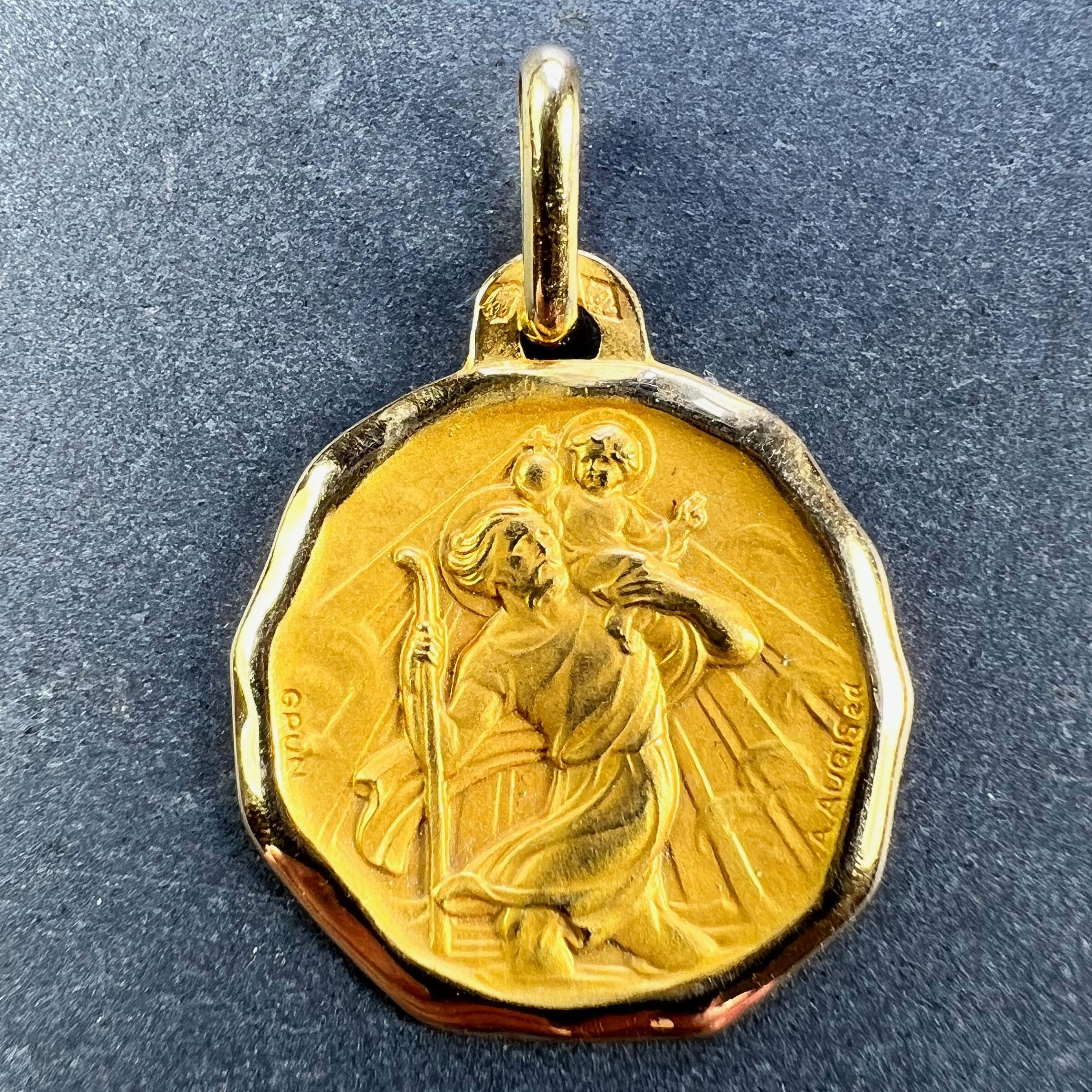 A French 18 karat (18K) yellow gold charm pendant or medal designed by Grun for Augis depicting St Christopher carrying the infant Christ across the river. Stamped with the eagle's head for French manufacture, Augis' makers mark, and signed A. Augis