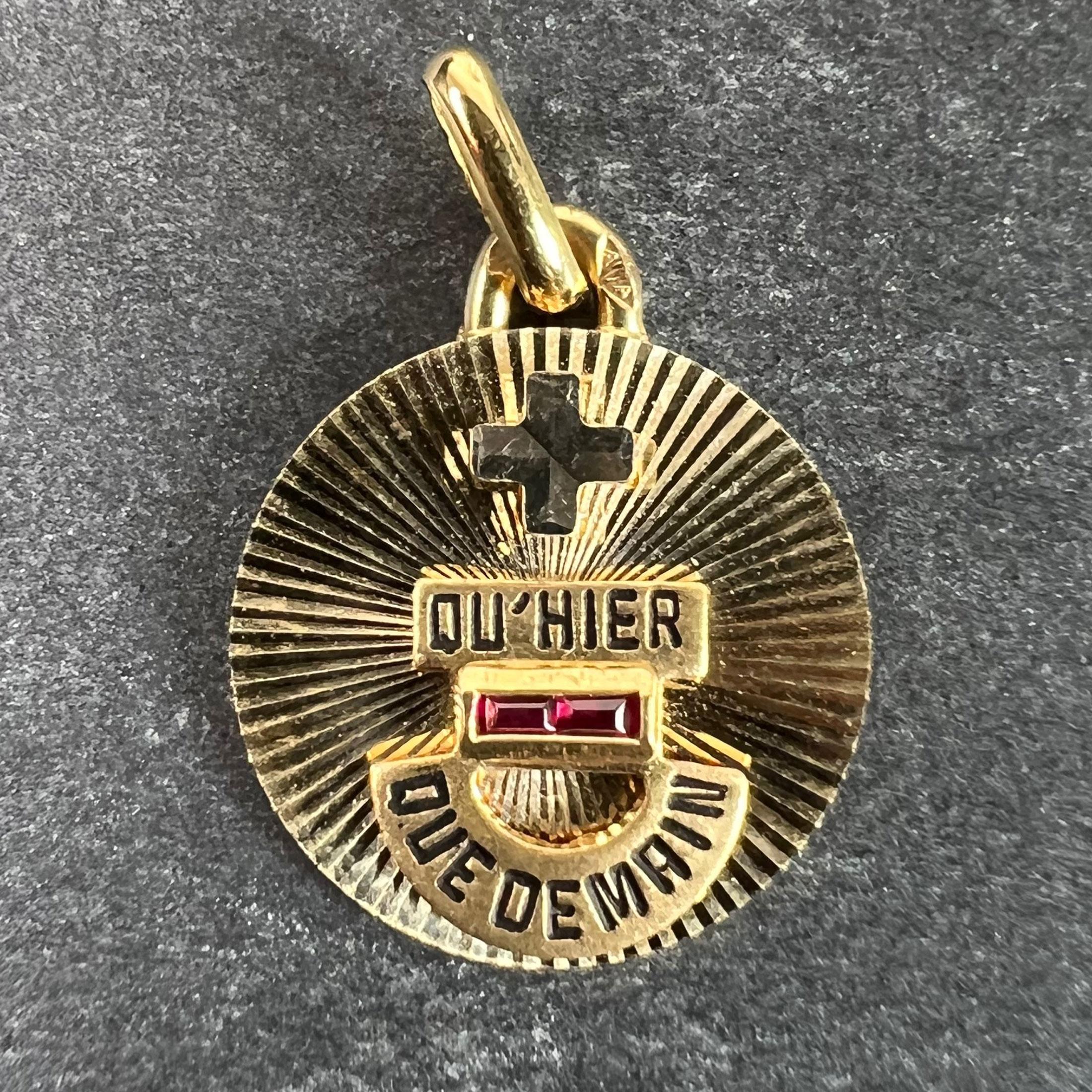 A French 18 karat (18K) yellow and white gold and lab created ruby love charm pendant with radiating ground and a black enamel rebus spelling out 