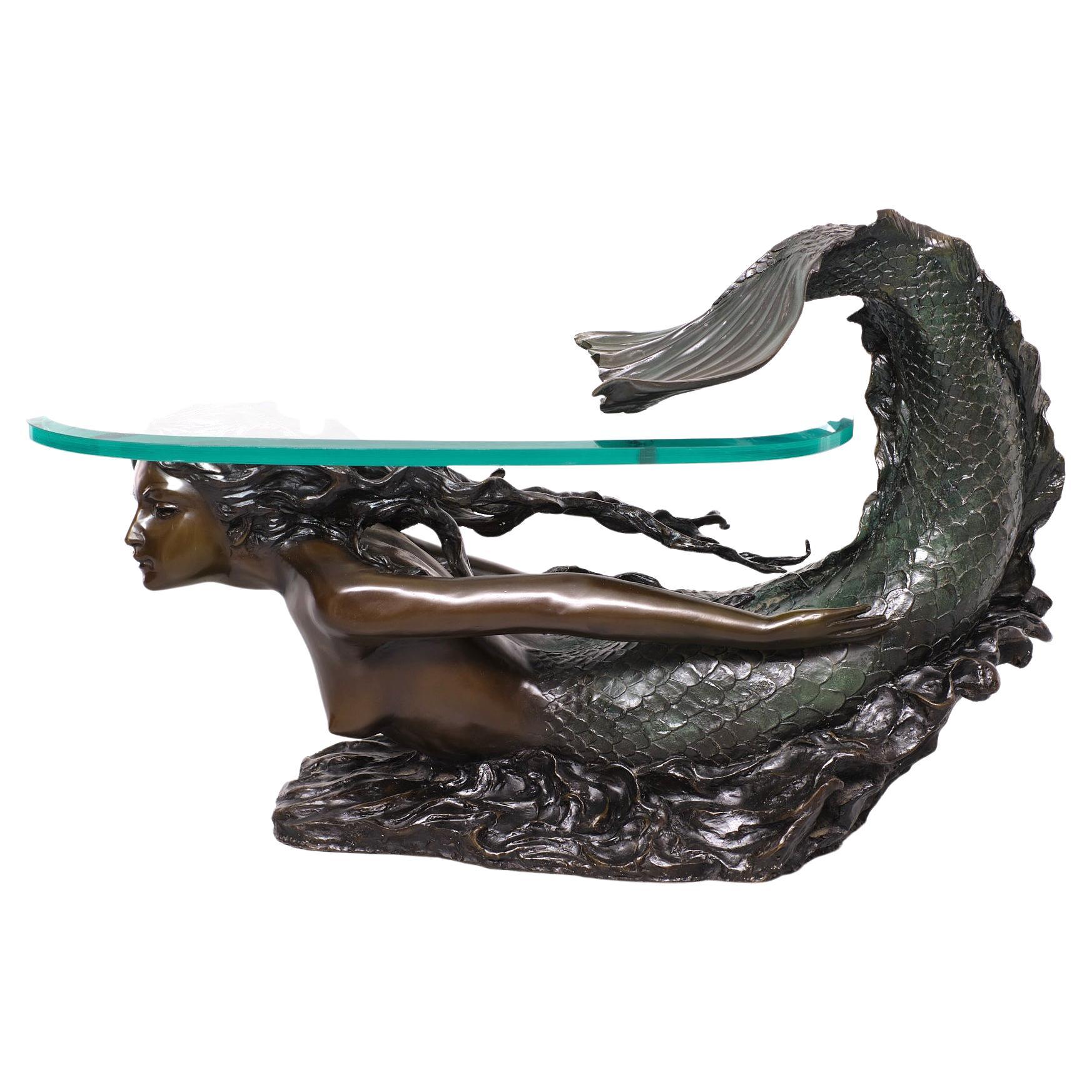 Beautiful Solid Bronze Mermaid coffee table ,After August Moreau 1834 -1917  
Superb patine .The tail with a Greenish patine . The body in a Brown patine .
comes with a thick cut glass top .  Striking piece . Love the way the tail off the 
Mermaid