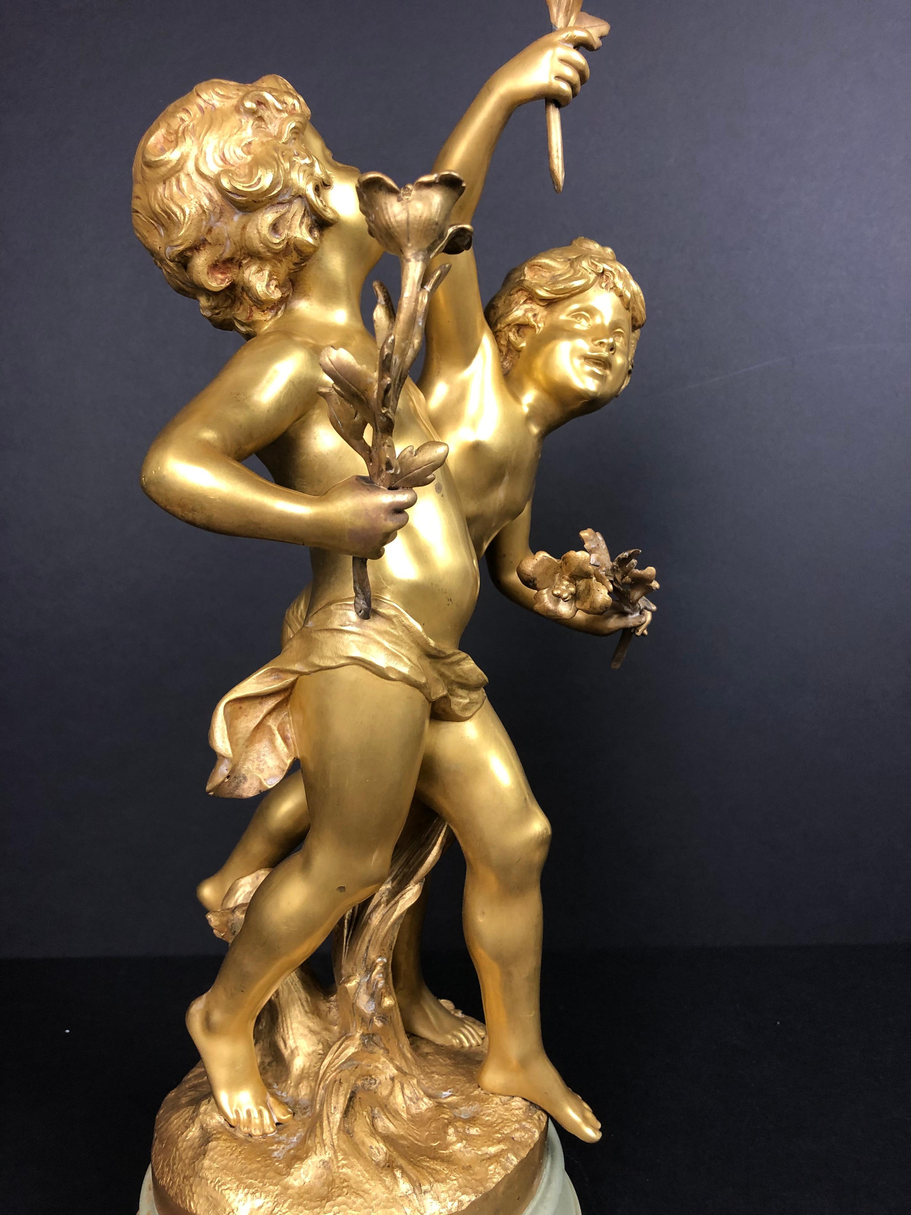 Auguste Moreau doré bronze figural group of children. Original 19th century fine quality doré bronze sculptural group of a young boy and girl presenting flowers. Mounted on marble base with doré bronze ring at bottom. Signed on base.
Diameter of