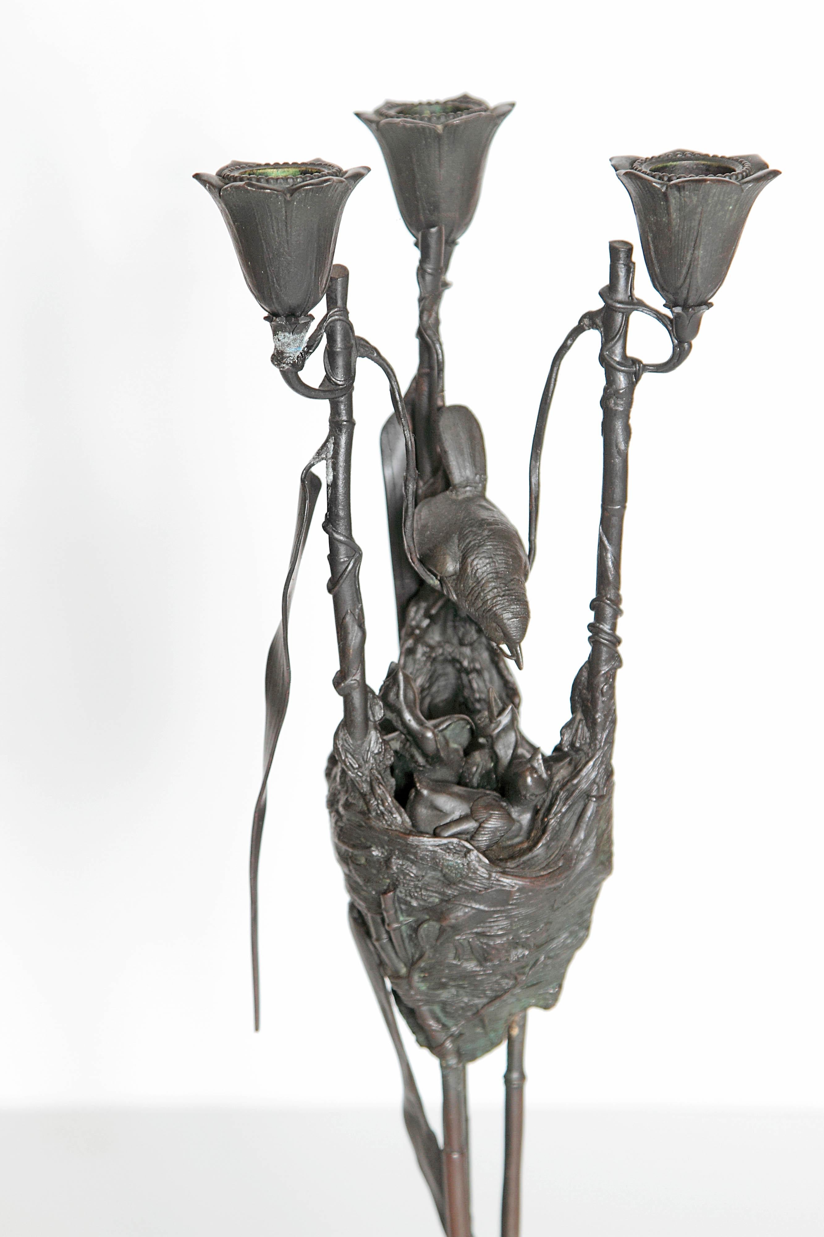 A pair of Art Nouveau bronze candelabra by Auguste-Nicolas Cain, (French 1821-1894). The bronze pieces artfully portray animals. The tripod base is formed from snails with their tiny antennae. One candelabra is a mother bird feeding her babies. On