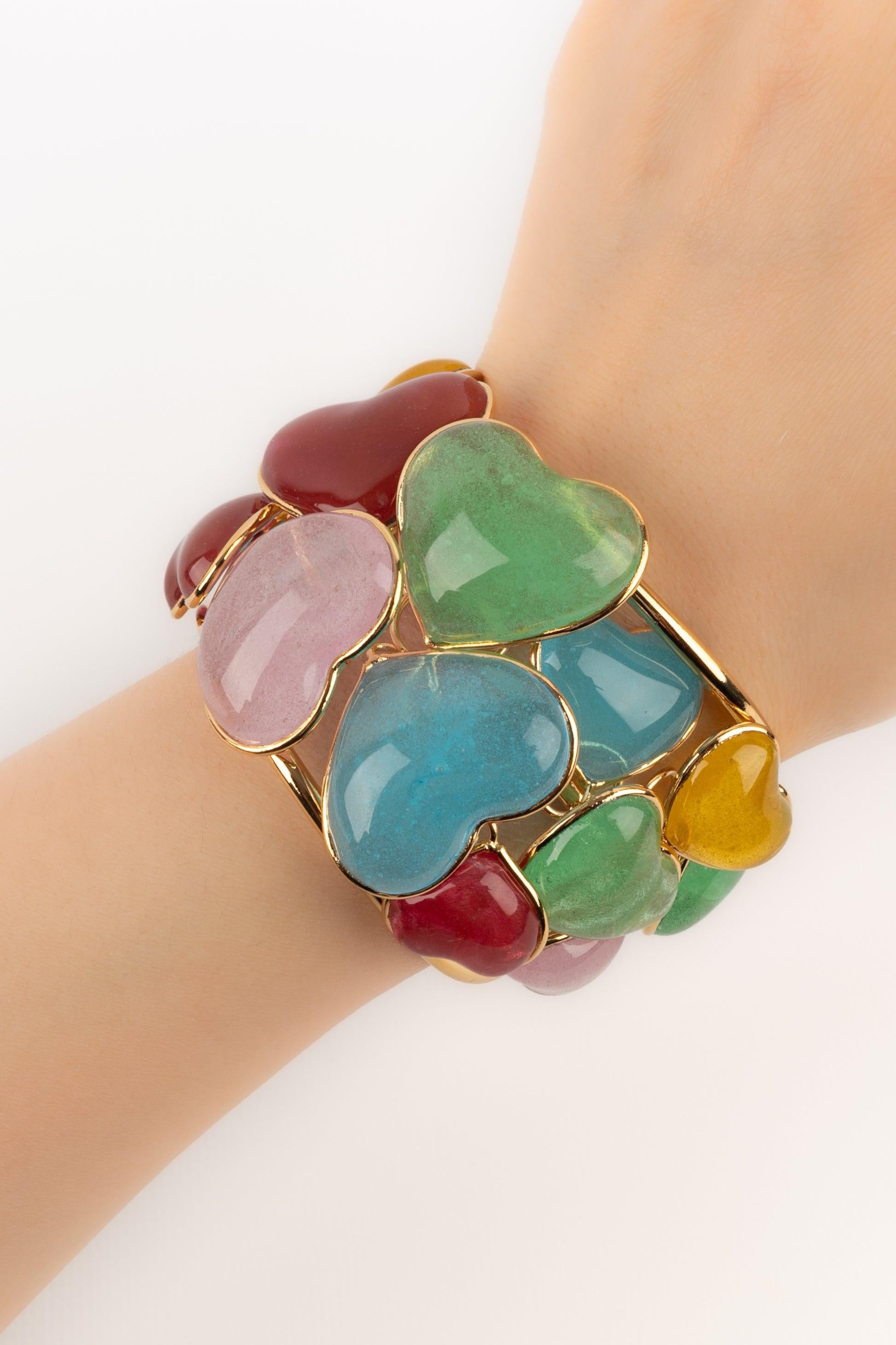 Augustine - (Fabriquée en France) Bracelet manchette en métal doré et cœurs en pâte de verre colorée.

Informations complémentaires :
Condit : Très bon état.
Dimensions : Circonférence : 13,5 cm - Ouverture : 2,5 cm - Largeur : 4 cm

Référence du