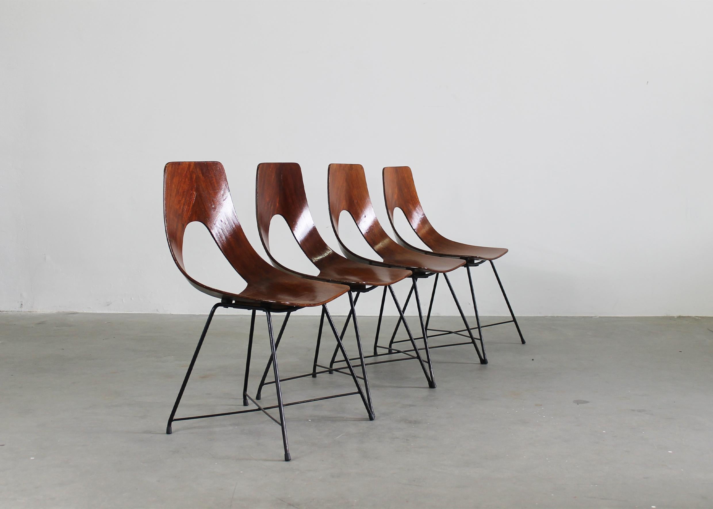 Set of four dining chairs model Ariston with structure in curved plywood and black lacquered metal legs. 
The Ariston chair was designed by Augusto Bozzi and manufactured by Saporiti during the 1950s (the manufacturer's label is visible under the
