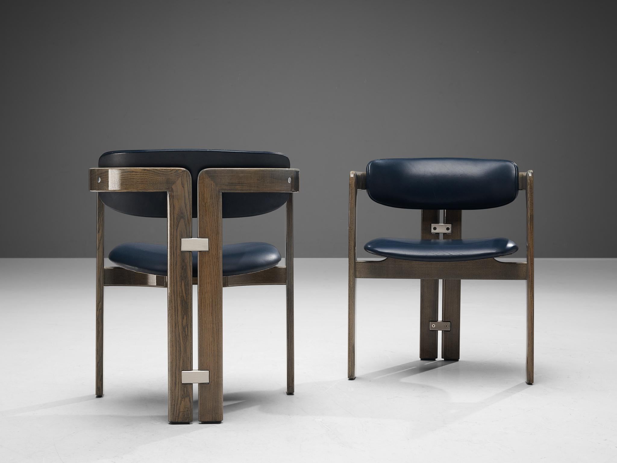 Augusto Savini for Pozzi, pair of 'Pamplona' dining chairs, oak, blue leather upholstery, aluminum, Italy, 1965.

Pair of armchairs in walnut and blue leather upholstery. A characteristic design; simplistic yet very strong in lines and