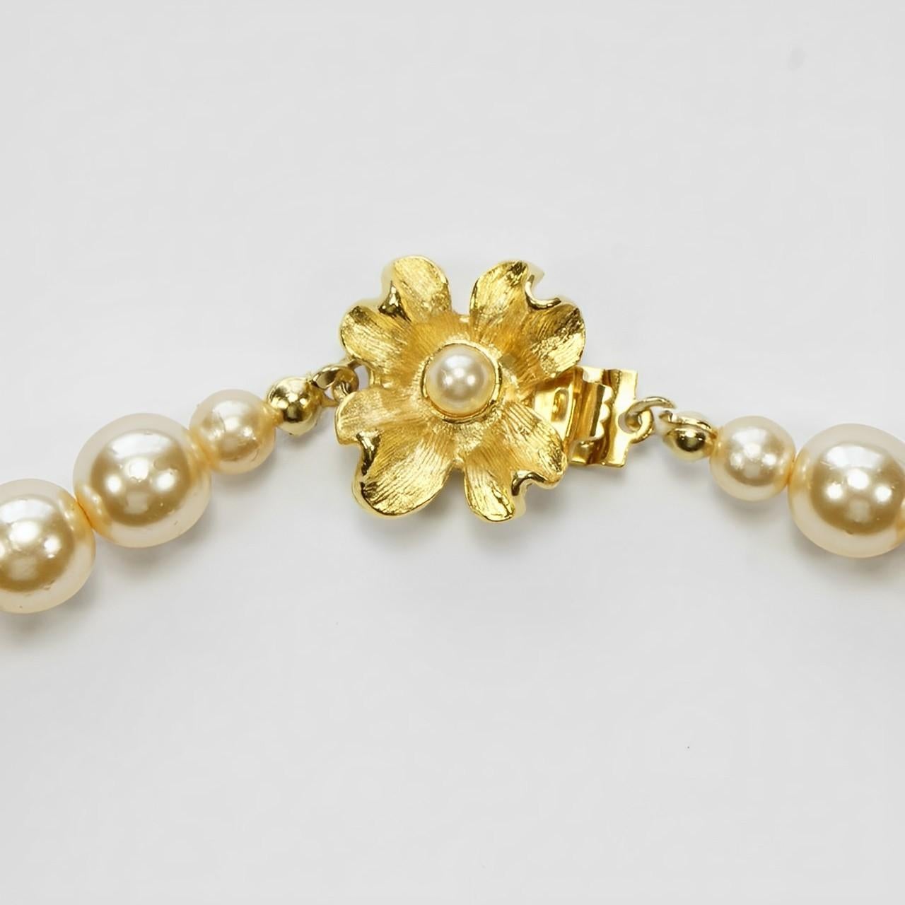 Lussuosa collana di perle in vetro champagne con chiusura a fiore placcata oro 22k e perla incastonata. Lunghezza 42,2 cm / 16,6 pollici. Le perle sono di 7,5 mm / .29 pollici. La collana è in ottime condizioni, con un paio di graffi alle