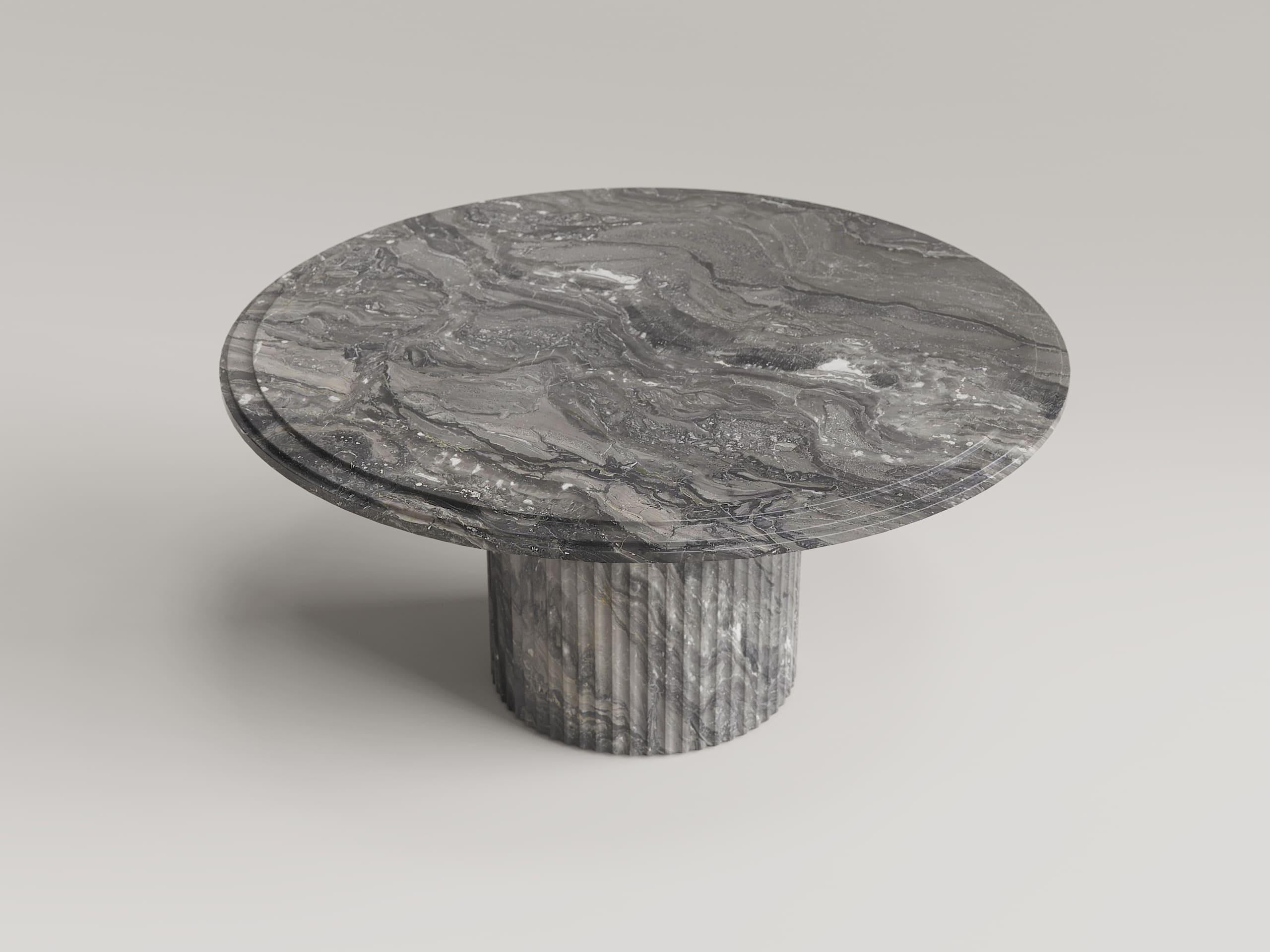 Un mueble que combina escultura y funcionalidad. Esta mesa redonda está hecha de mármol Arabescato Grigio Orobico, una famosa piedra natural italiana extraída en los valles de Bérgamo, reconocible por su fondo predominantemente gris enriquecido por