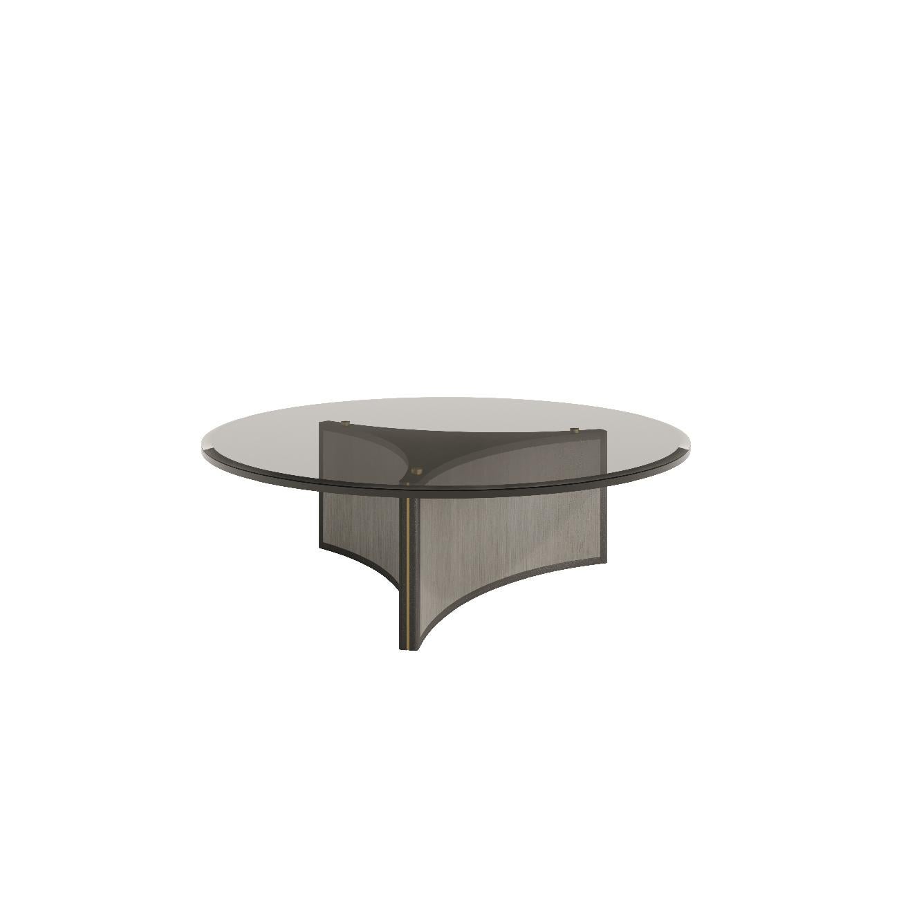 Der runde Couchtisch Aura zeichnet sich durch sein anmutiges, rundes Design aus und ist wahlweise mit einer Glas- oder Natursteinplatte ausgestattet. 

Seine konkaven Beine, die mit Details aus antikem Messing verziert sind, verleihen ihm einen