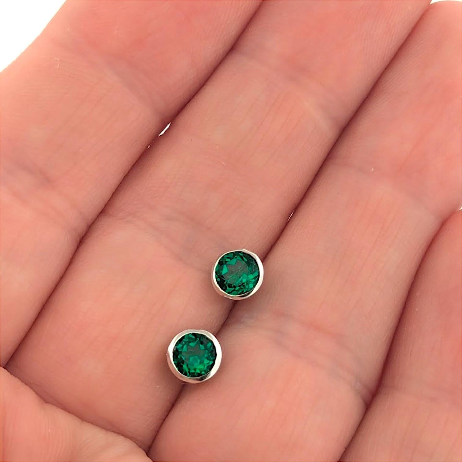 Les boucles d'oreilles Aurelia sont une célébration raffinée de la couleur et de l'artisanat, mettant en valeur des émeraudes rondes créées de 1,10 carat dans des montures élégantes en or blanc 10 carats radieux. Leur teinte vert vif et leur design