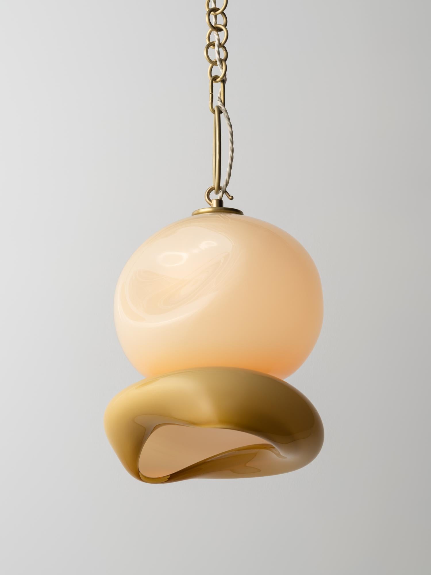 Der Aurelia-Anhänger erinnert an eine Mondqualle und ist aus geschichtetem mundgeblasenem Glas mit einer zarten Messingkette gefertigt. Es ist Teil der Marea Collection - eine Erkundung organischer Formen, inspiriert von Meeresleben und