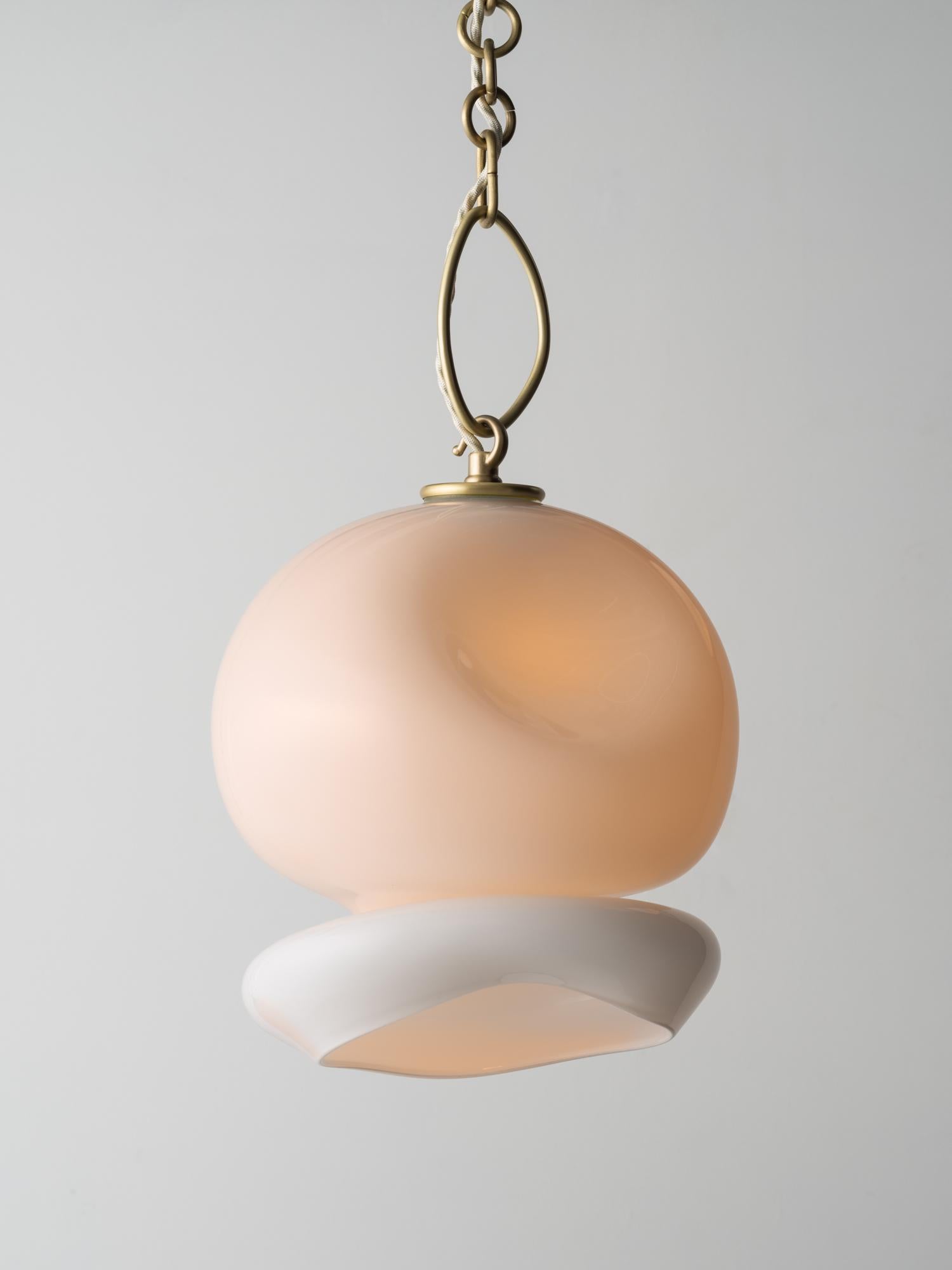 Der Aurelia-Anhänger erinnert an eine Mondqualle und ist aus geschichtetem mundgeblasenem Glas mit einer zarten Messingkette gefertigt. Es ist Teil der Marea Collection - eine Erkundung organischer Formen, inspiriert von Meeresleben und
