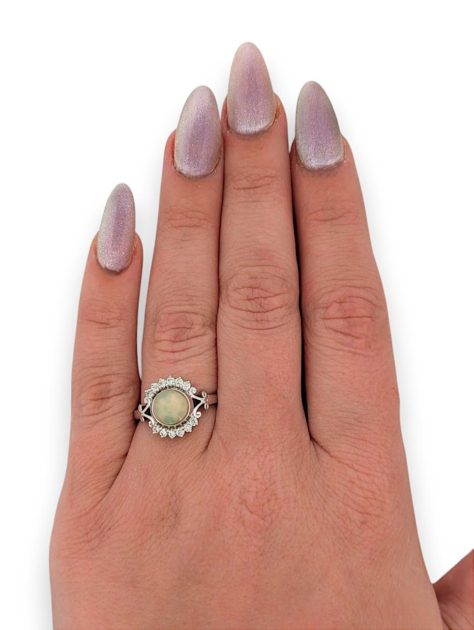 L'anello Aurelie è una graziosa miscela di eleganza e misticismo, con un'opale luminosa da 1,05 carati incastonata nell'oro bianco 14 carati e impreziosita da scintillanti diamanti naturali. Questo incantevole design cattura la bellezza mutevole