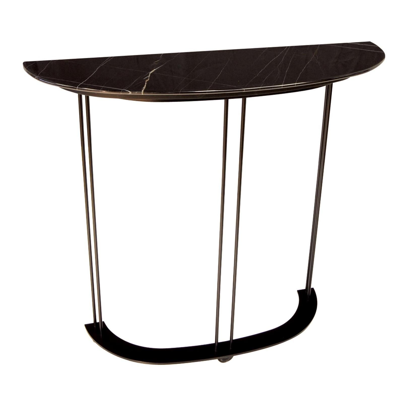 Defined by a sleek and timeless design, this striking tall console boasts a demilune profile with a top in black Nero Guinea, distinctive for its vibrant and dynamic veining. The three column-like legs with a matte black powder coating connect to a