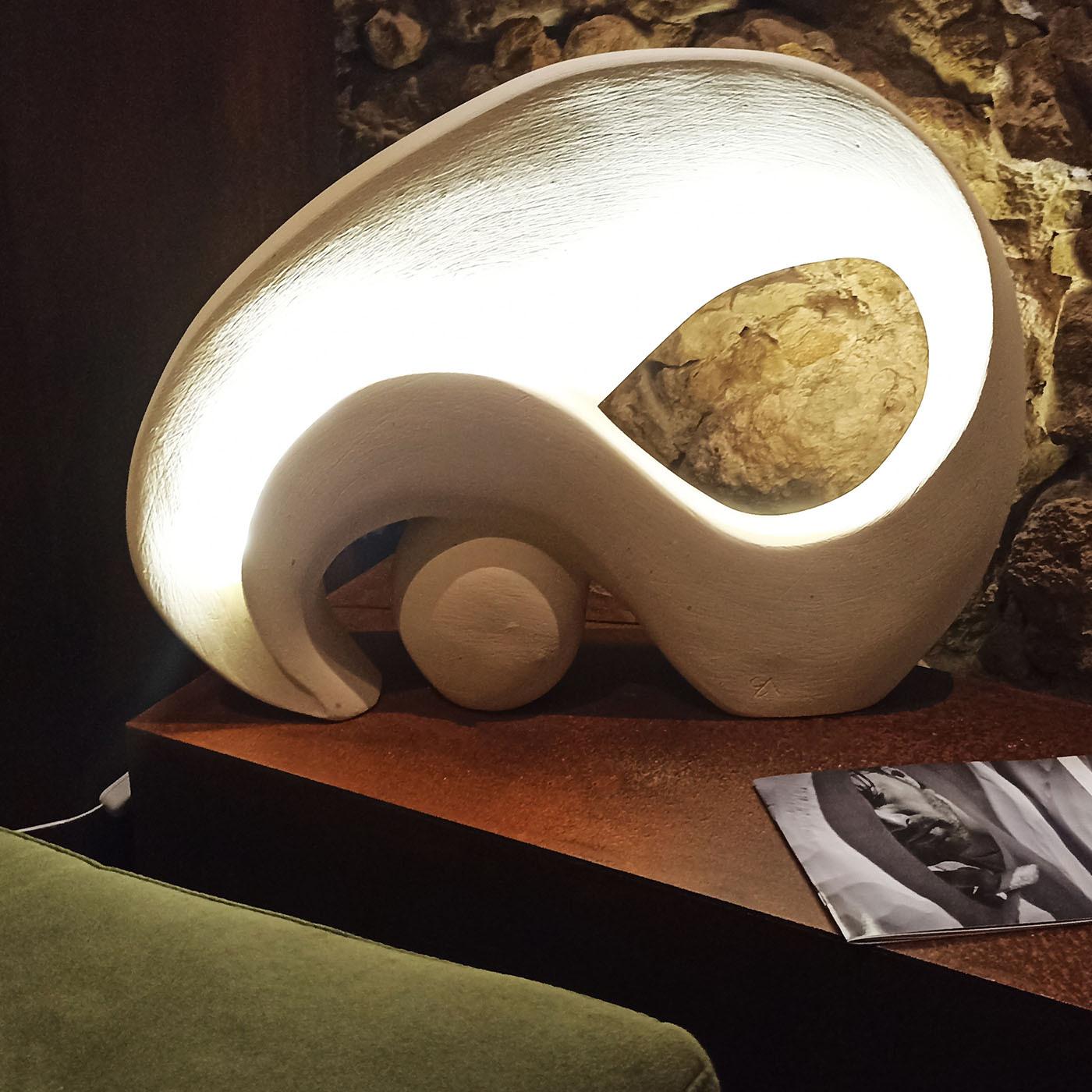 Des lignes épurées et sinueuses définissent cette stupéfiante sculpture lumineuse, un design unique issu d'une série exclusive créée des mains de l'artiste Andrea Serra. D'un aspect naturellement brillant grâce à l'utilisation d'une pierre naturelle
