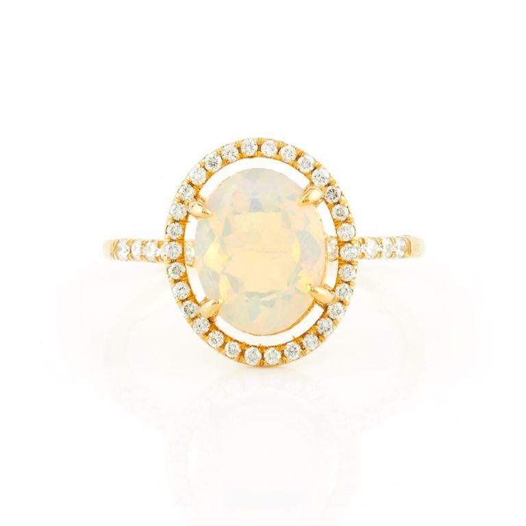 Inspired by the beauty of constellations, this stunning 14kt yellow gold ring features a mesmerizing 10x8mm Ethiopian opal as its centerpiece. A radiant halo of 40 sparkling diamonds orbits the opal, creating a celestial glow. Weighing 3.2g in gold,