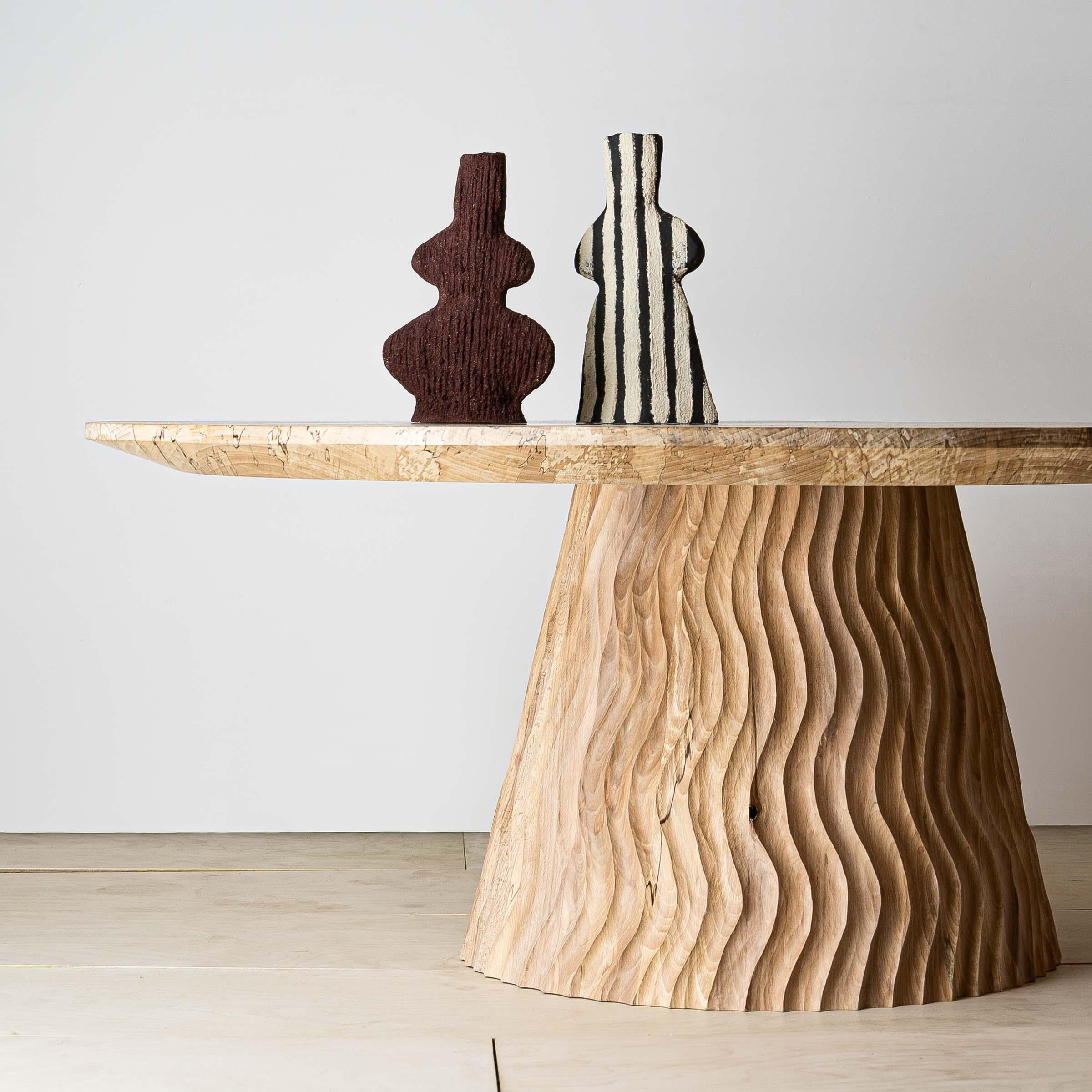 A sculptural centrepiece, the Aurora coffee table is made from solid English beech. The piece features a wavy hand-carved base, with visible chisel marks to reveal the hand of the maker. The construction of the hollow conical base draws on