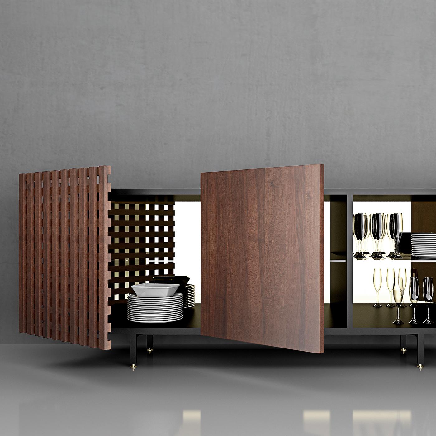 Questa credenza in legno laccato opaco dal fascino contemporaneo vanta ante rivestite in noce canaletto e un ripiano interno in vetro trasparente. Una delle ante, in legno massiccio, mostra un design aperto di linee perpendicolari che lascia