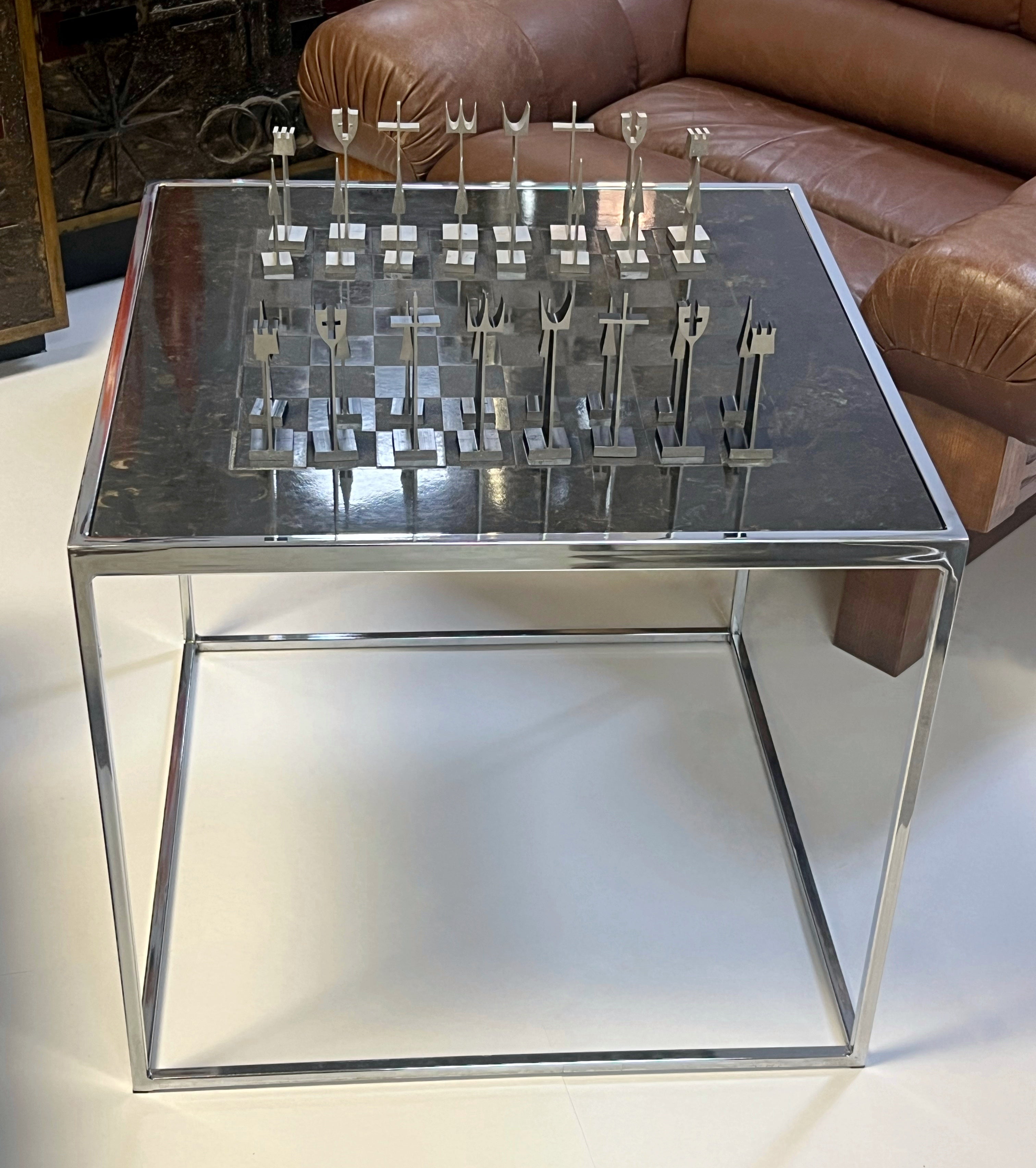 A chess set by Austin Enterprises. Chrome and faux slate table. The pieces come in a costume acrylic display case. 