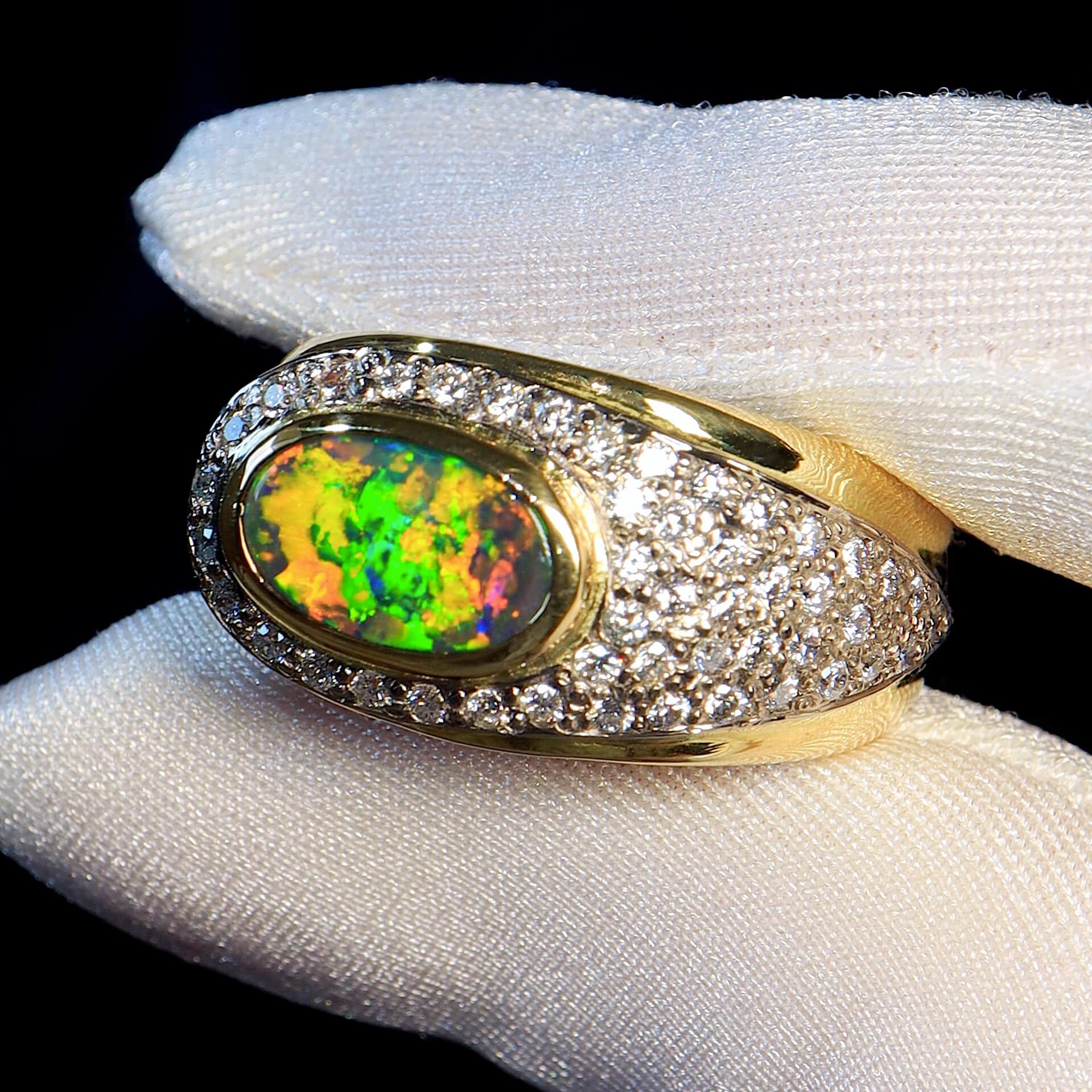 Elegant and sophisticated, this stunning solid 18K yellow and white gold ring features a mystical solid Australian Black Opal with shimmering orange, yellow, blues and greens that take you into its depths and hold your imagination in awe. 

The
