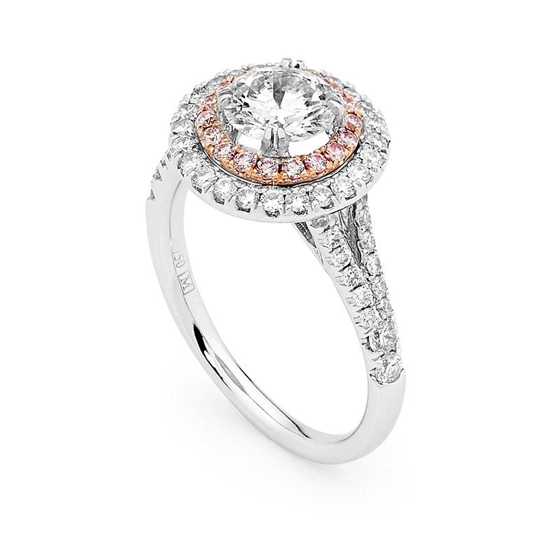This stunning Matthew Ely engagement ring features a 1.02ct Round Brilliant Cut White diamond GIA certified (color E, clarity SI) coming from the Argyle mine in Western Australia and a Twin Diamonds Halo, containing a first halo of 16 rare Argyle