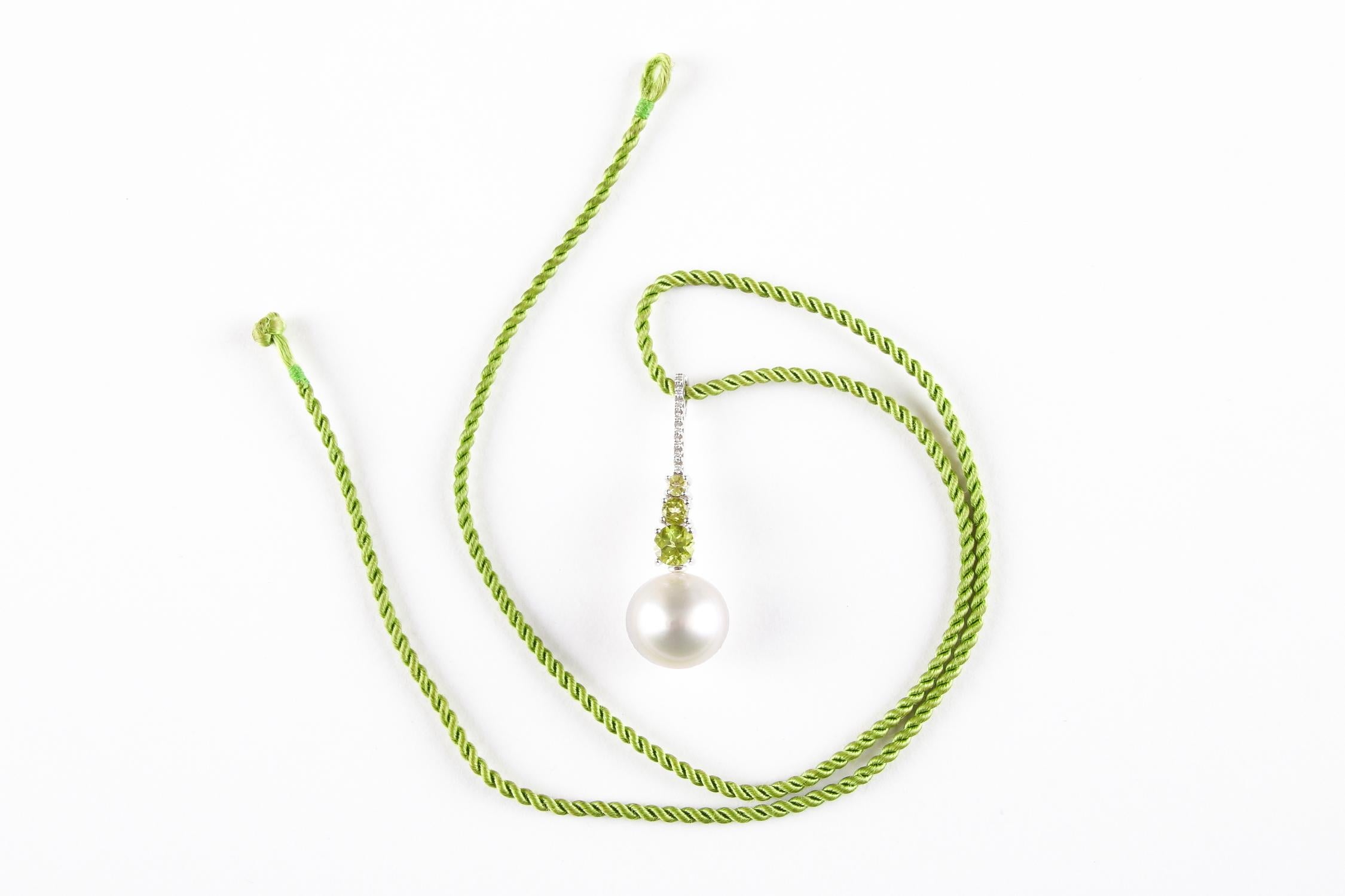 From the exclusive award winning Australian jewellers Autore, this is a really stunning pendant.

The pendant features a cultured South Sea pearl, measuring 14.1mm, suspended from a line of three graduated circular-shape peridots below a