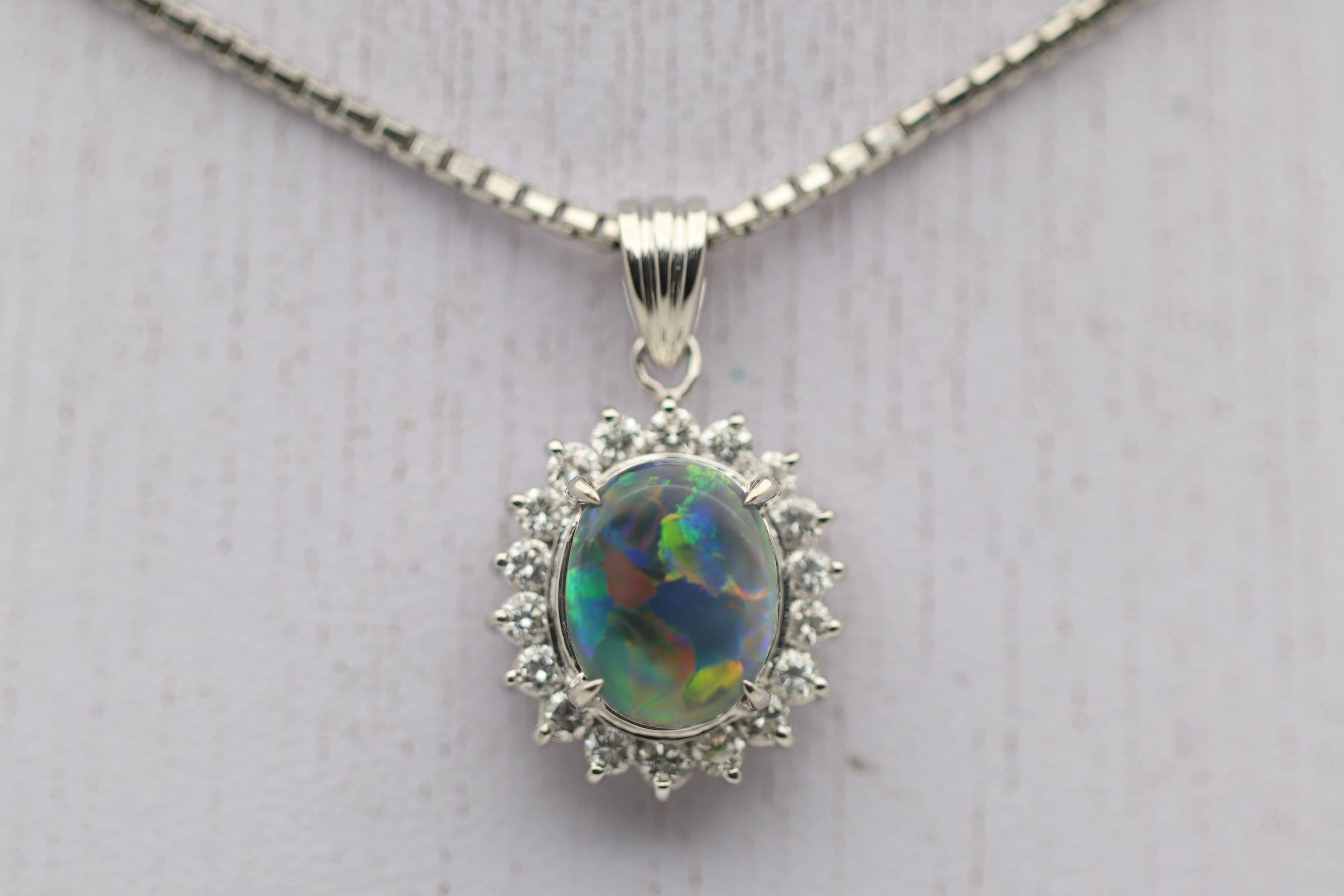 A classic and gemmy Australian black opal weighing 2.85 carats takes center stage of this platinum pendant. It has amazing play-of-color as bright intense flashes of red, orange, yellow, green and blue dance across the stone. It is surrounded by a
