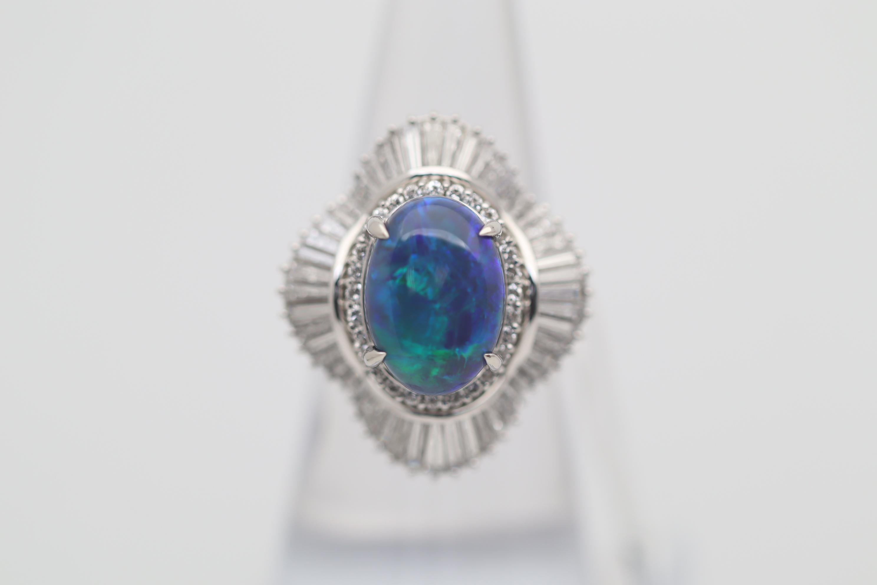 A large and impressive platinum cocktail ring featuring a natural Australian black opal! The opal weighs 4.60 carats and has great play of color as flashes of greens and blues dance across the stone. It is complemented by spiraling baguette and