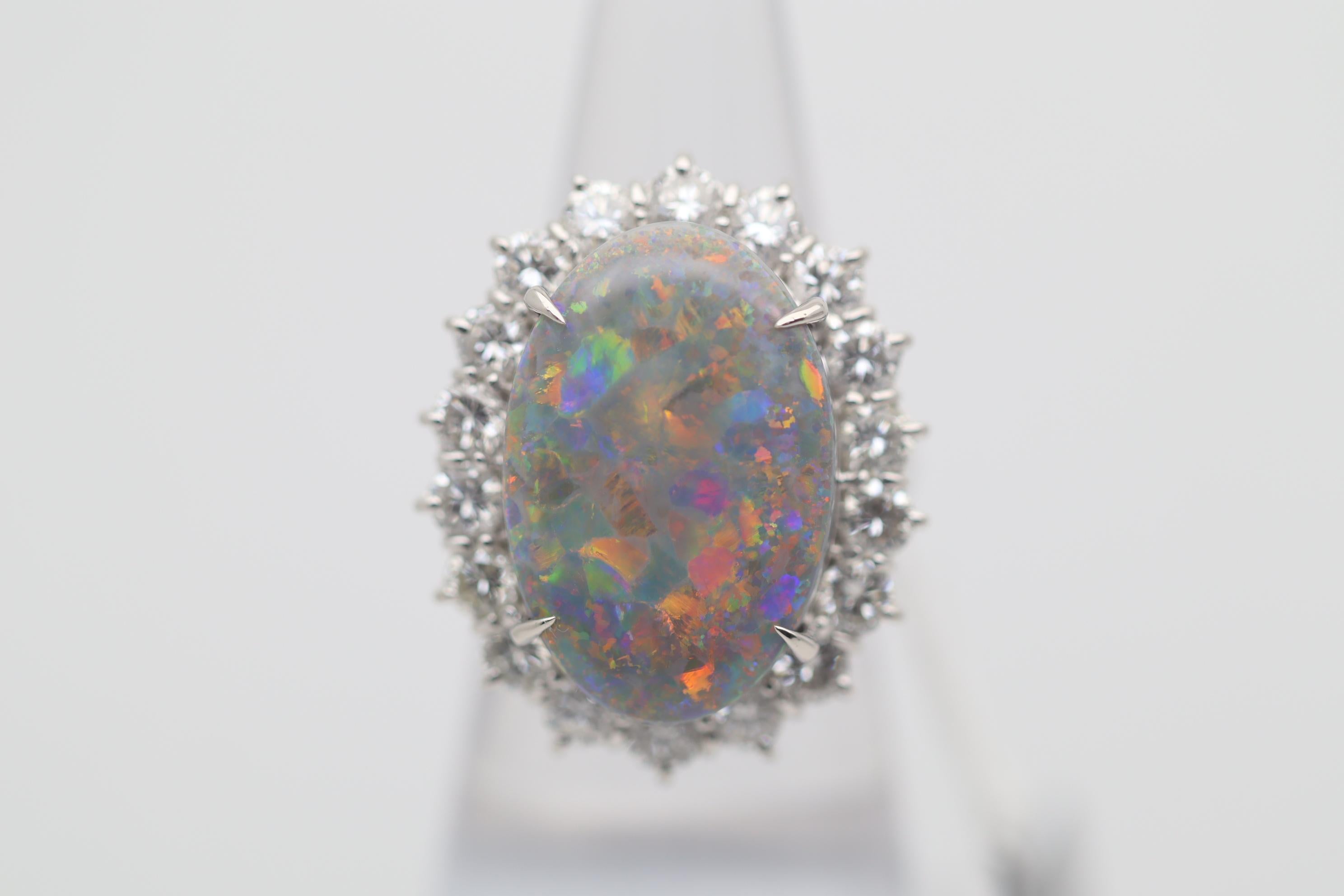 Une grande, impressionnante et magnifique opale noire d'Australie occupe le devant de la scène ! Il pèse 12,94 carats et présente un excellent jeu de couleurs, des éclats lumineux dansant sur l'ensemble de la pierre. Les couleurs principales sont