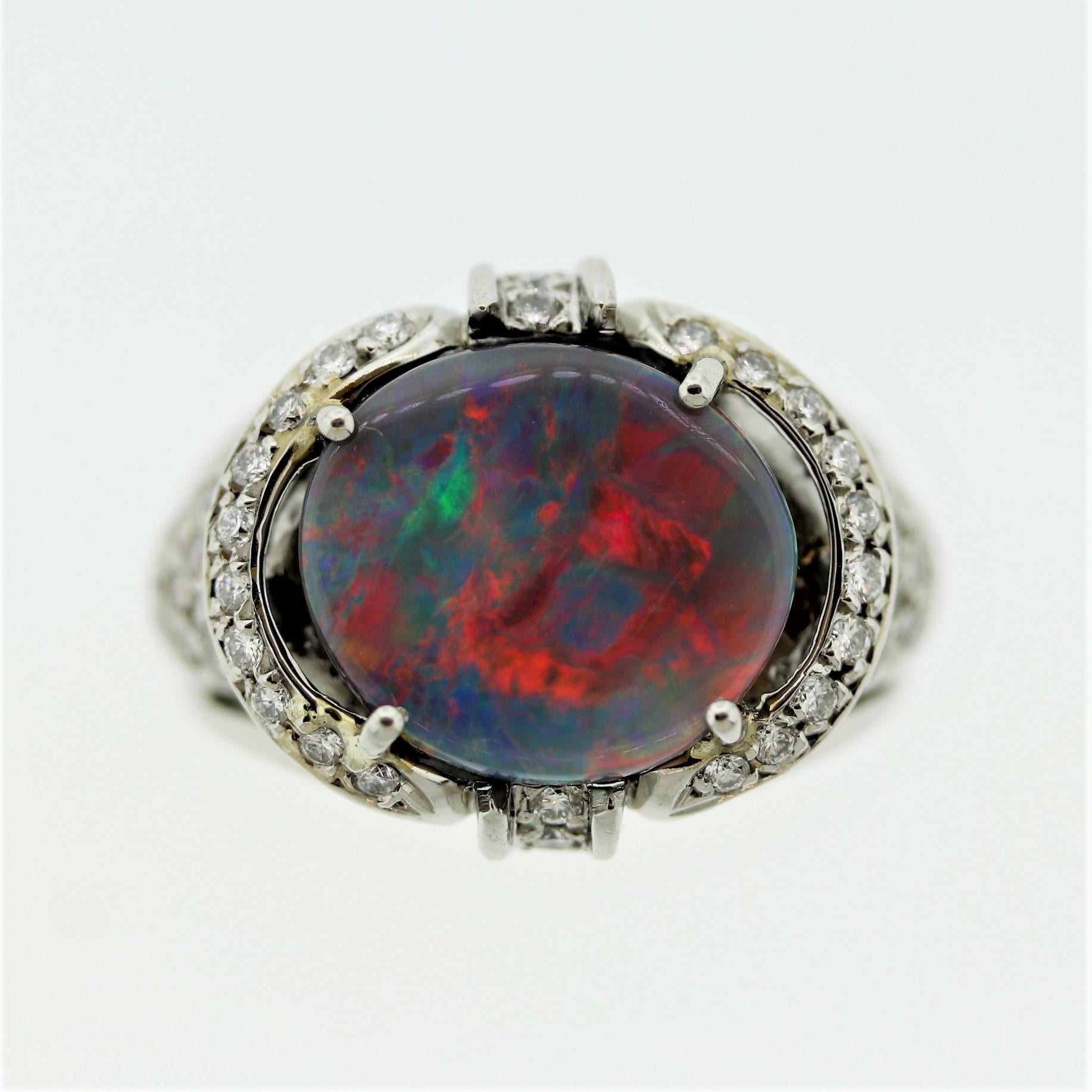 A classic Australian black opal with top-quality play of color! The 3.21 carat opal shows bright flashes of predominantly reds along with oranges, blues, and greens. A true beauty, it is accented by 0.46 carats of round brilliant-cut diamonds which