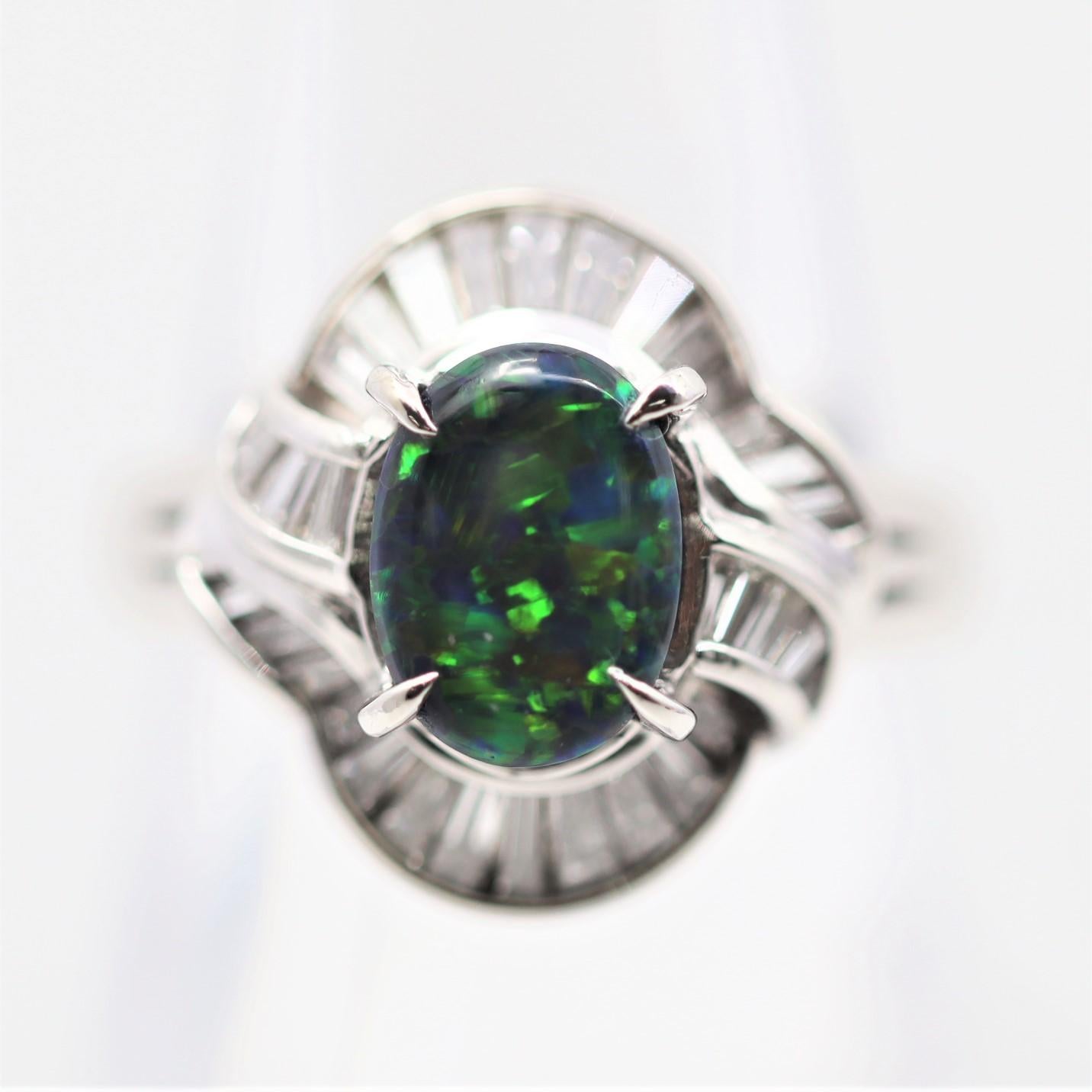 A sleek and elegant platinum ring featuring a 1.55 carat natural Australian black opal. It has great play of color as bright flashes of green, orange, and yellow dance across the dark black body color of the opal. It is complemented by 0.83 carat of