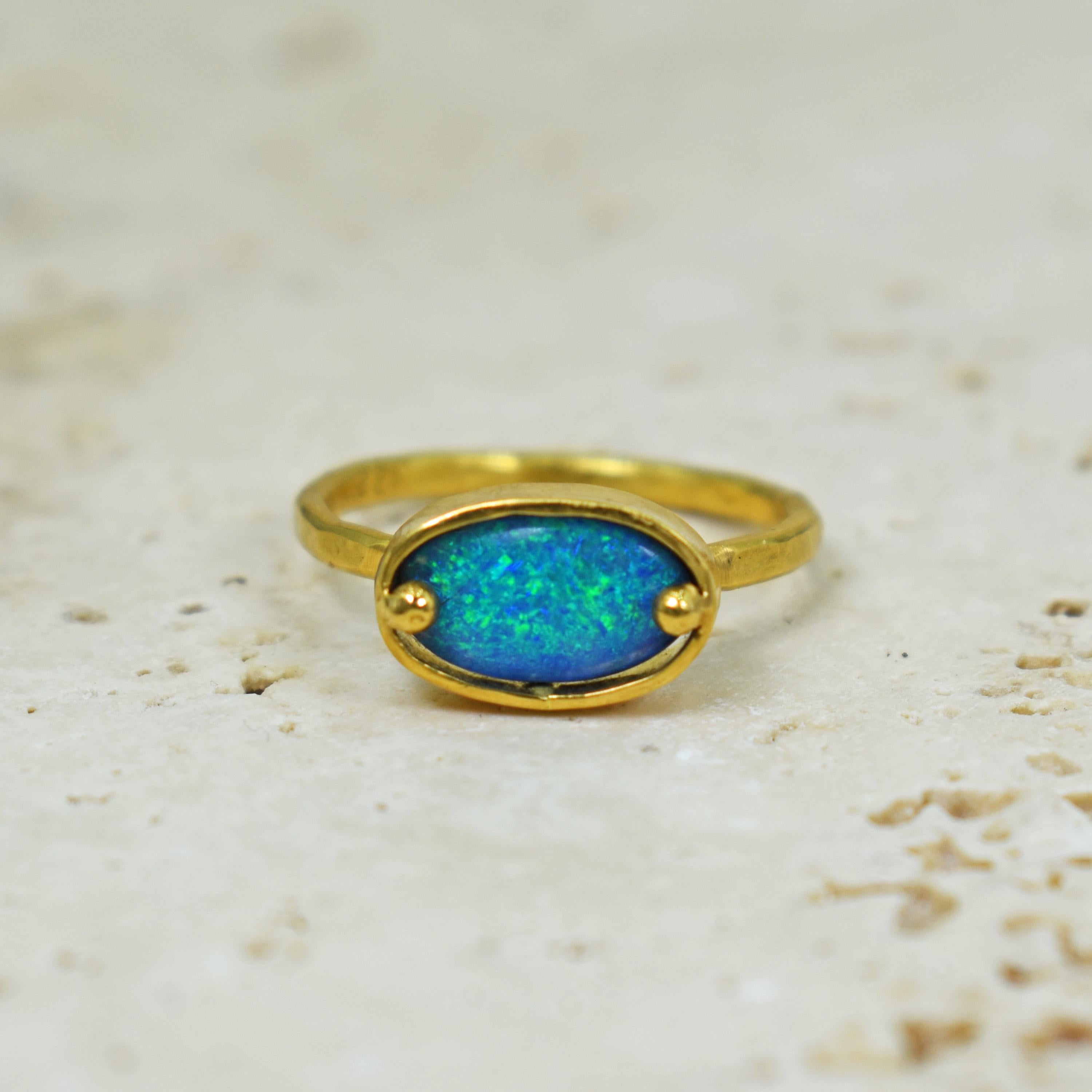 Blue Australian Opal 1.16 carat cabochon set in a textured, hand forged 22k yellow gold bezel and accent prong solitaire ring. This stunning green flash Opal paired with hammered, high karat gold fuses contemporary, minimalist elegance with old