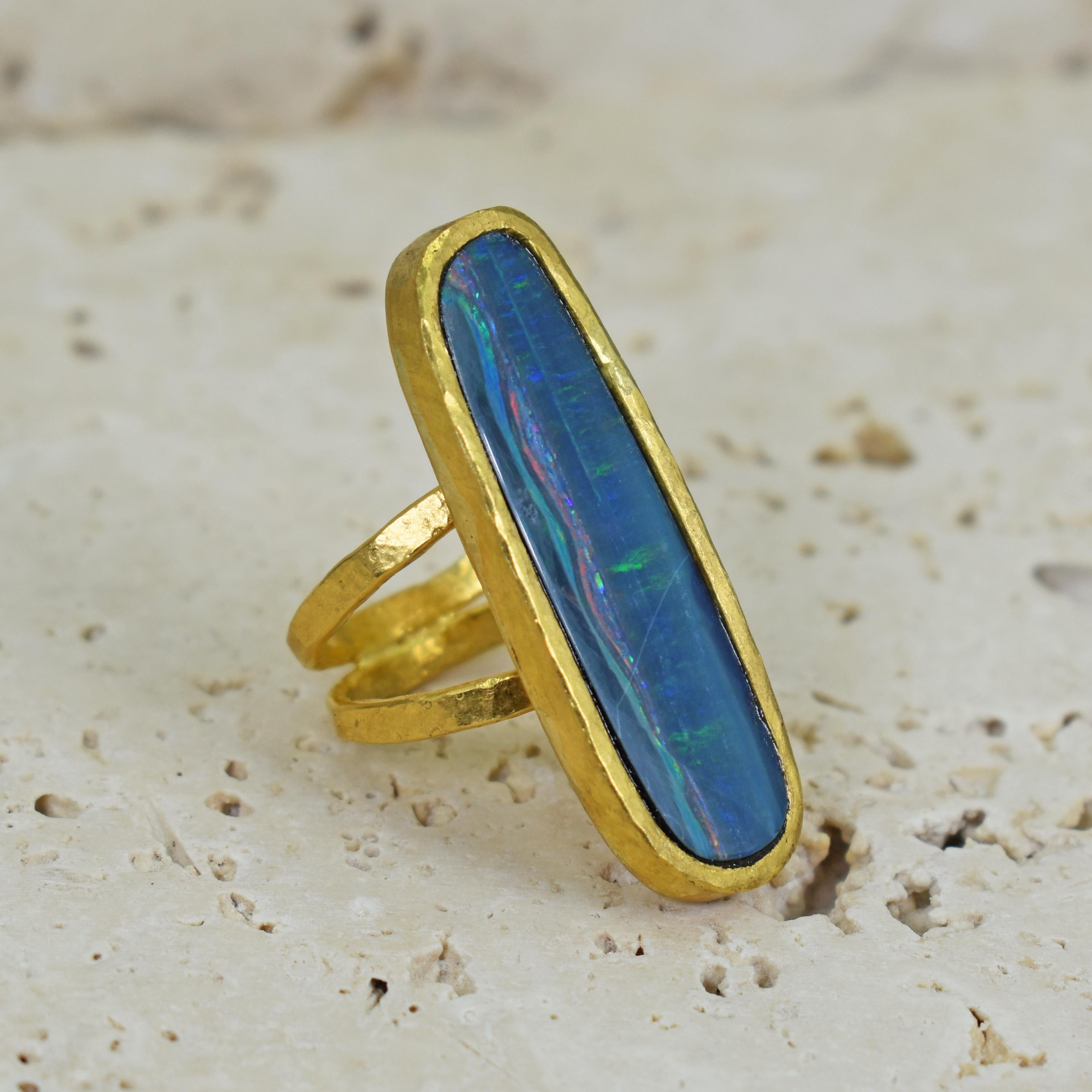 Australian Boulder Opal and solid 22k hand forged yellow gold solitaire cocktail ring with a split shank design. This stunning, elongated blue Opal with rainbow flashes paired with the hammered, high karat gold fuses old world jewelry crafting