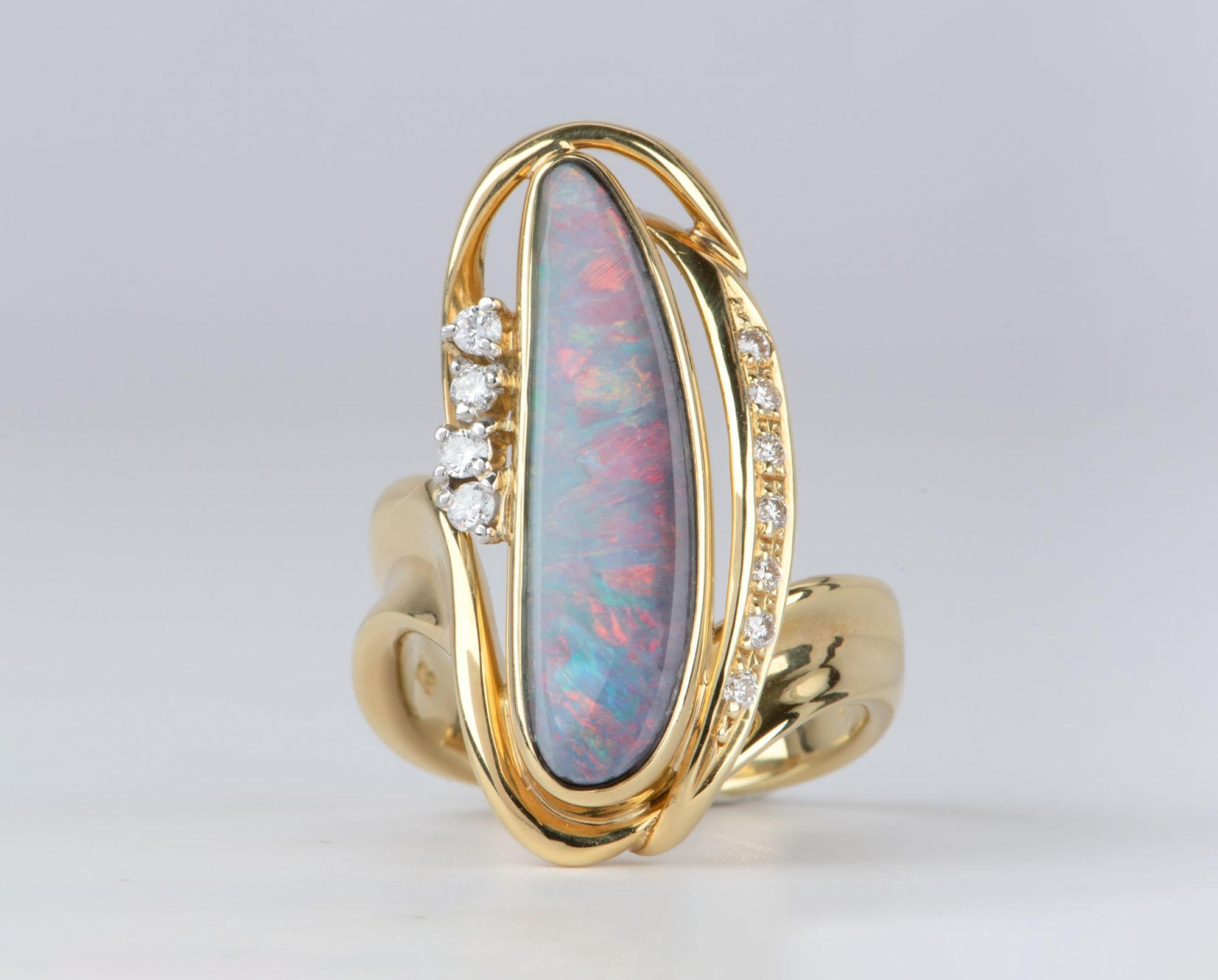 This Australian Boulder Opal and Diamond Ring in 18K Gold is a stunning piece of jewelry that will turn heads! Its elongated shape complements the beautiful opal that beams with bright red, blue, and orange flashes. Its incomparable sparkle and