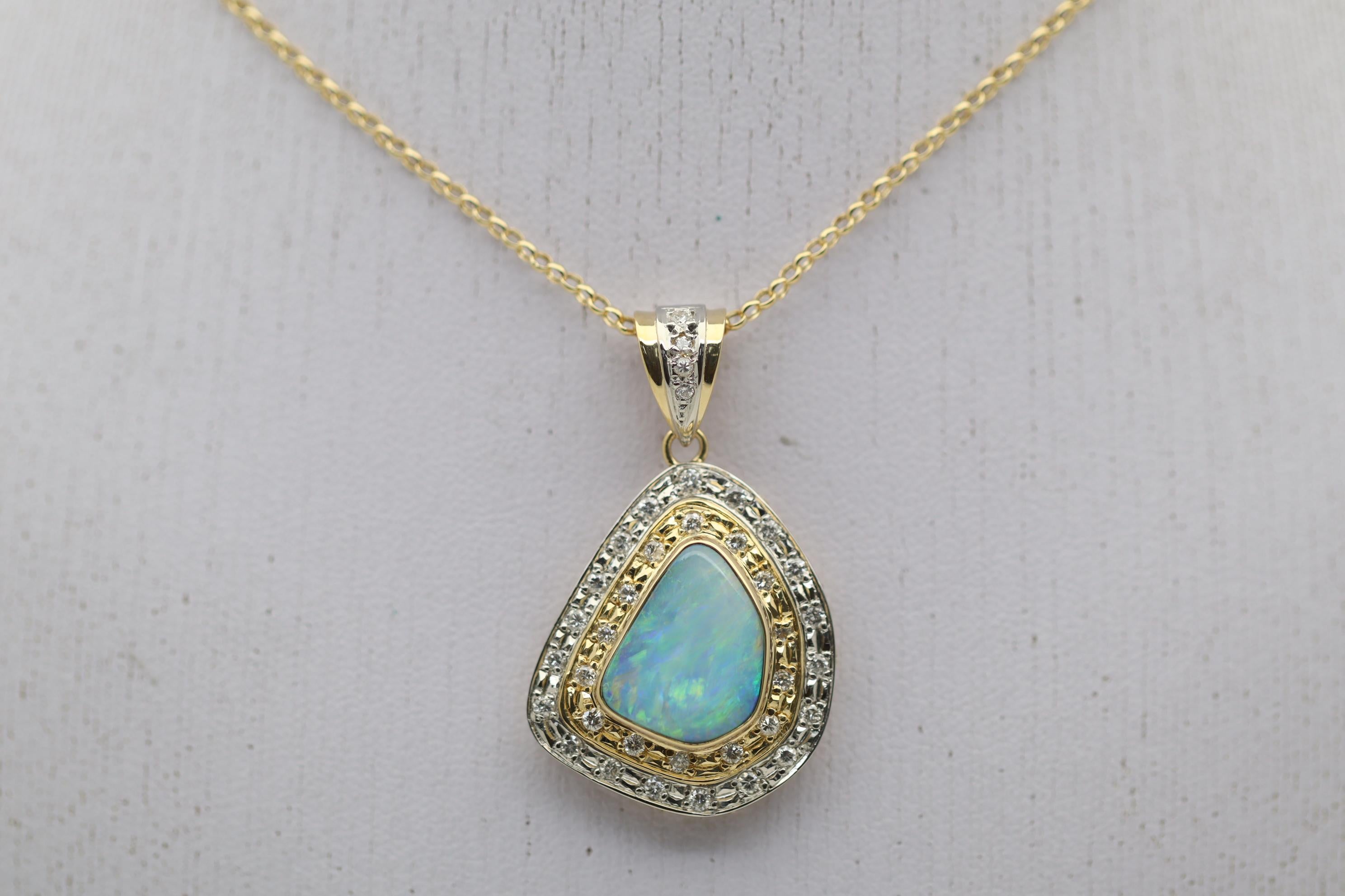 A stylish pendant featuring a natural Australian boulder opal set in a two-tone gold and platinum pendant. The opal weighs 3.10 carats and has green, yellow, blue, and orangy-red play-of-color. It is complemented by 0.59 carats of round