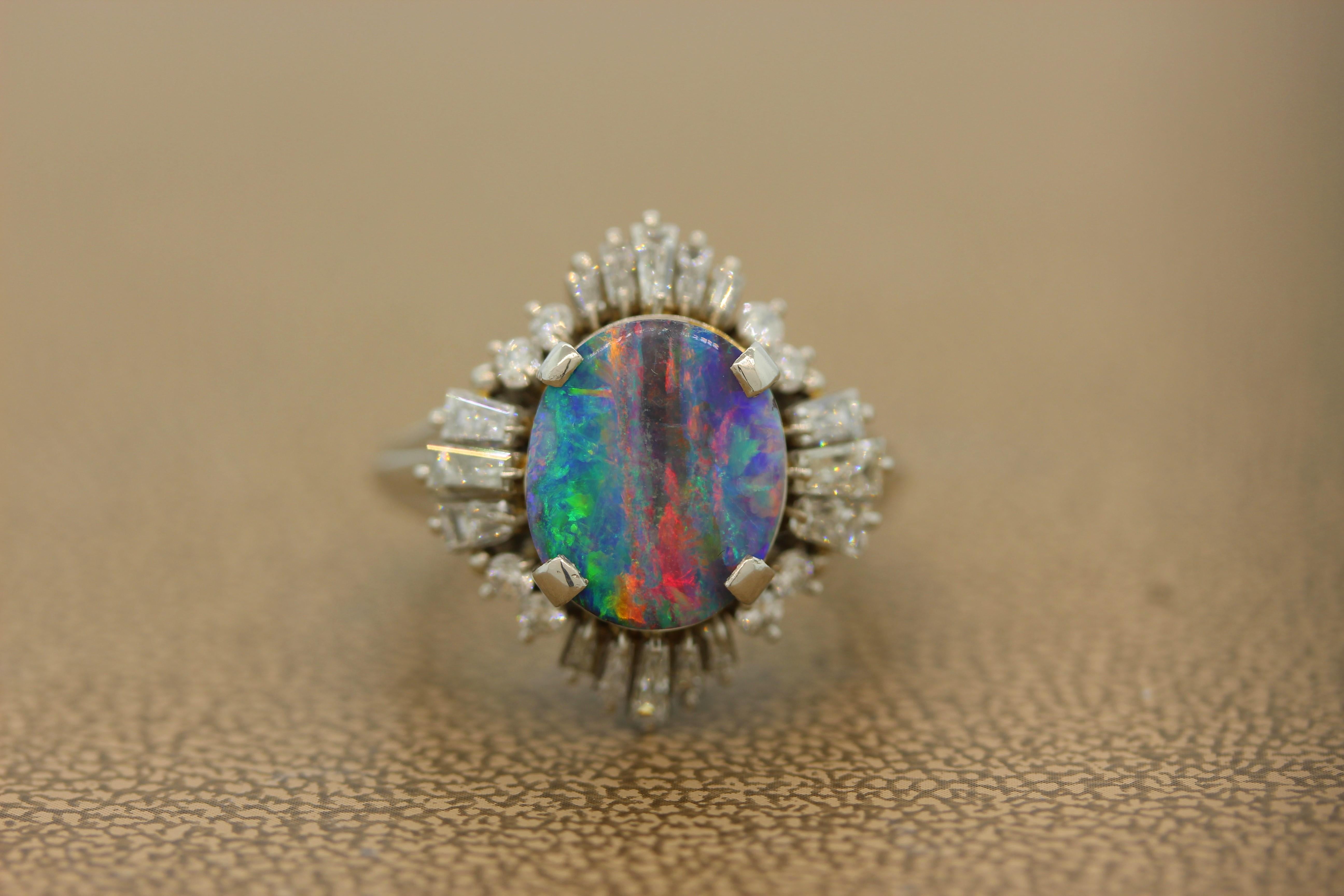 A beautiful ring featuring a gem 4.73 carat boulder opal with all the colors in the spectrum. Strong flashes of red, blue, green and purple can all be seen on this gem opal. It is haloed by 1.05 carats of baguette and round cut diamonds in a