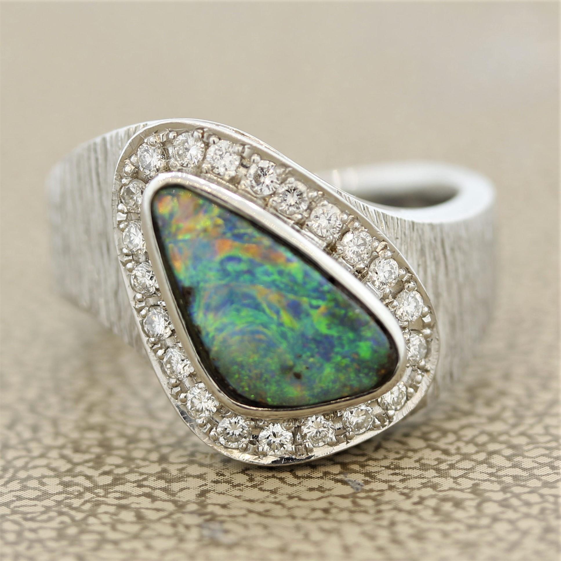 A lovely platinum ring featuring a 1.46 carat boulder opal from Australia. It has great play of color as swirls of green and blue as well as hints of orangy reds can be seen on the opal. It is accented by 0.28 carats of round brilliant cut diamonds