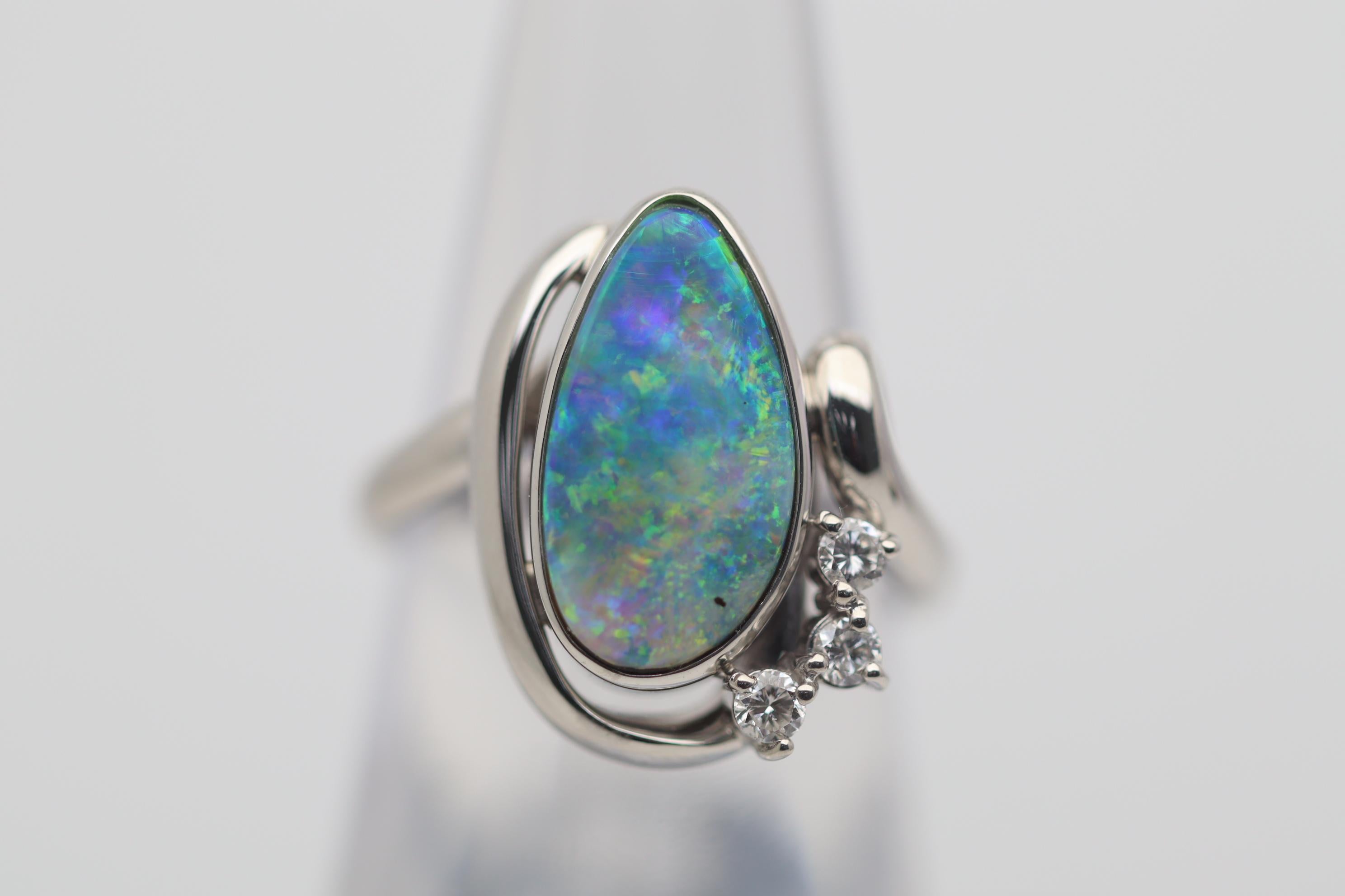 A fine boulder opal from Australia with excellent play-of-color. The 3.85 carat gem opal shows a bright array of greens, blues, yellows, and some oranges. It is complemented by 3 round brilliant-cut diamonds weighing 0.09 carats. Hand-fabricated in