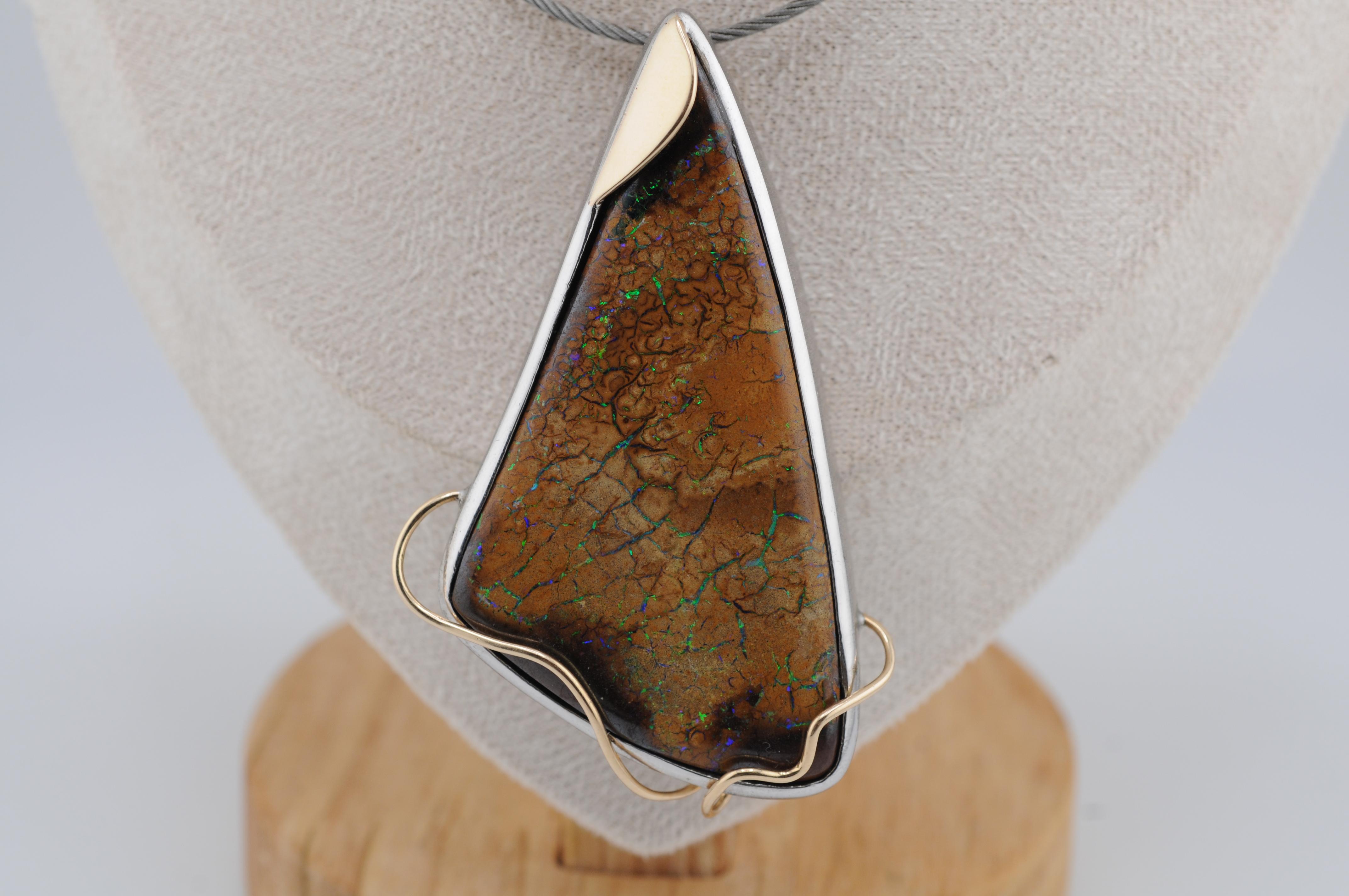 Ein auffälliger Anhänger mit einem natürlichen Boulder-Opal aus Queensland, Australien. Gefasst in massivem 925er Sterlingsilber mit raffinierten Akzenten aus 18 Karat Gelbgold. Das Stück zeichnet sich durch ein lebendiges Farbspiel und ein kühnes,