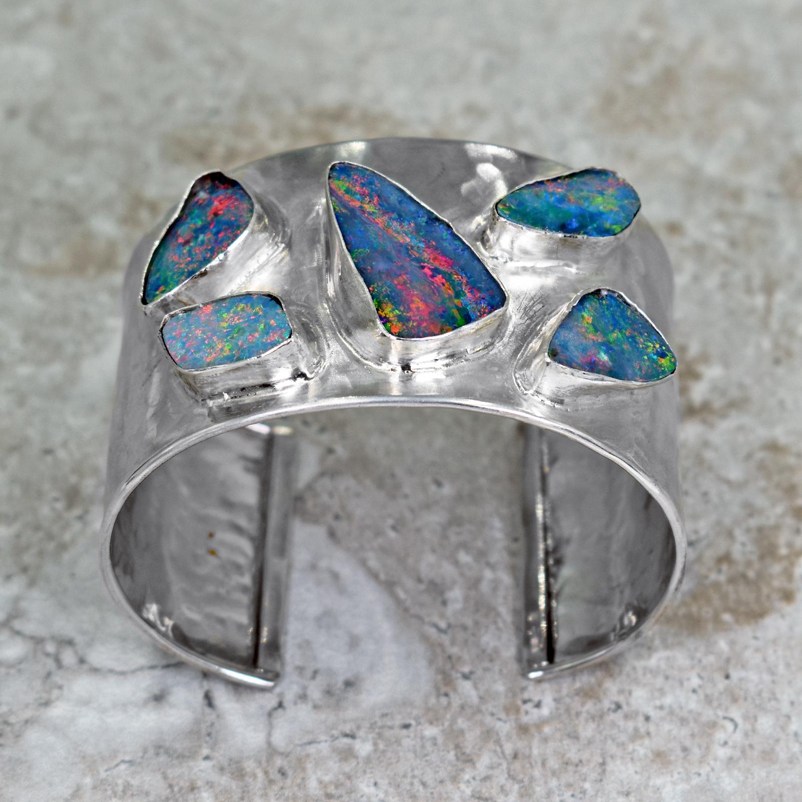 Five, gorgeous Australian Boulder Opals set in a hammered, sterling silver wide cuff bracelet with a brushed finish. Silver cuff is 1.5 inches wide. Inside of bracelet is 2.32 inches in width and bracelet opening is 1.07 inches wide, but is