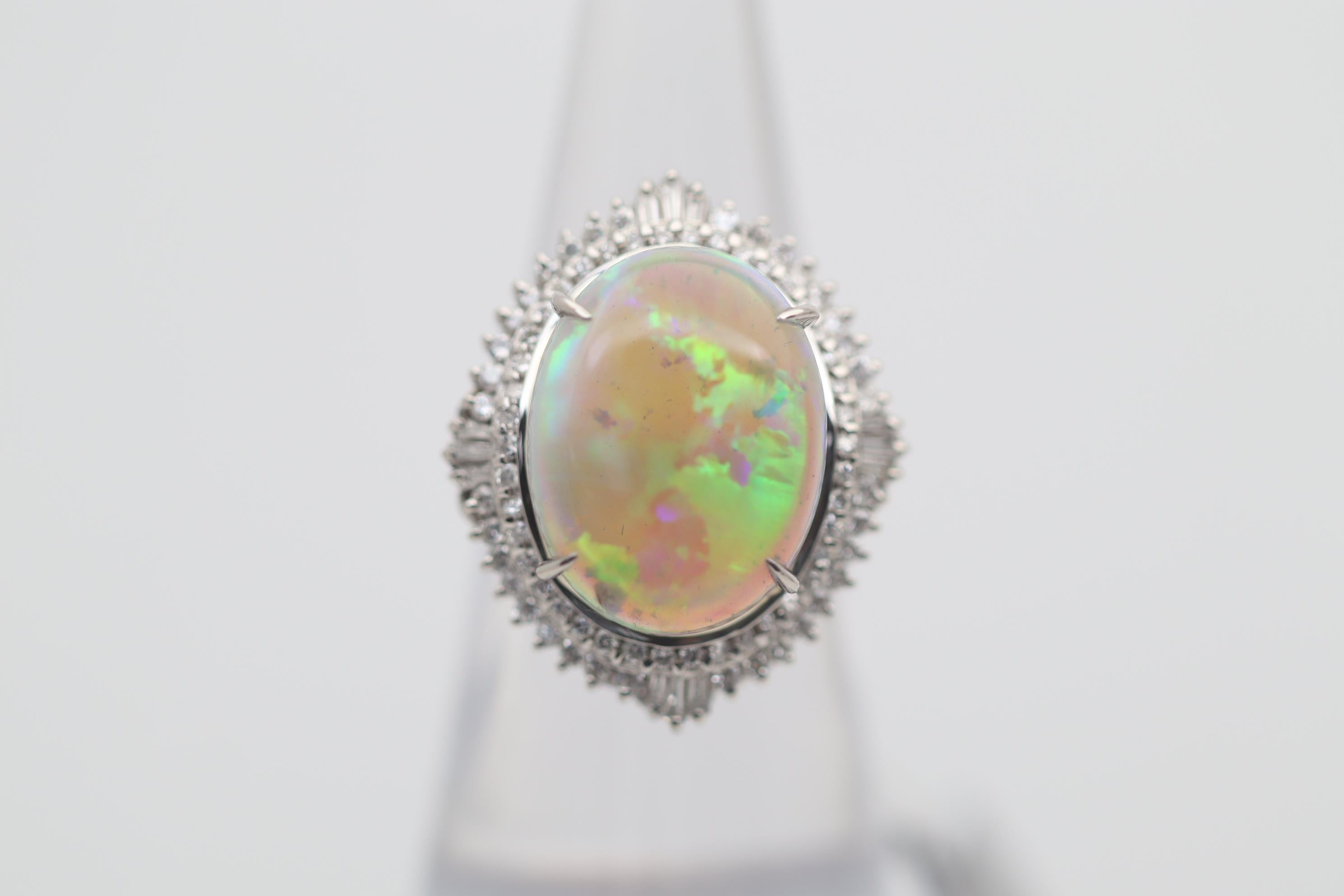A large fine crystal opal from Australia weighing 5.97 carats. It has fantastic play-of-color as big bright flashes of green, blue, yellow roll across the stone. Surrounding the opal are 0.79 carats of round brilliant and baguette-cut diamonds set