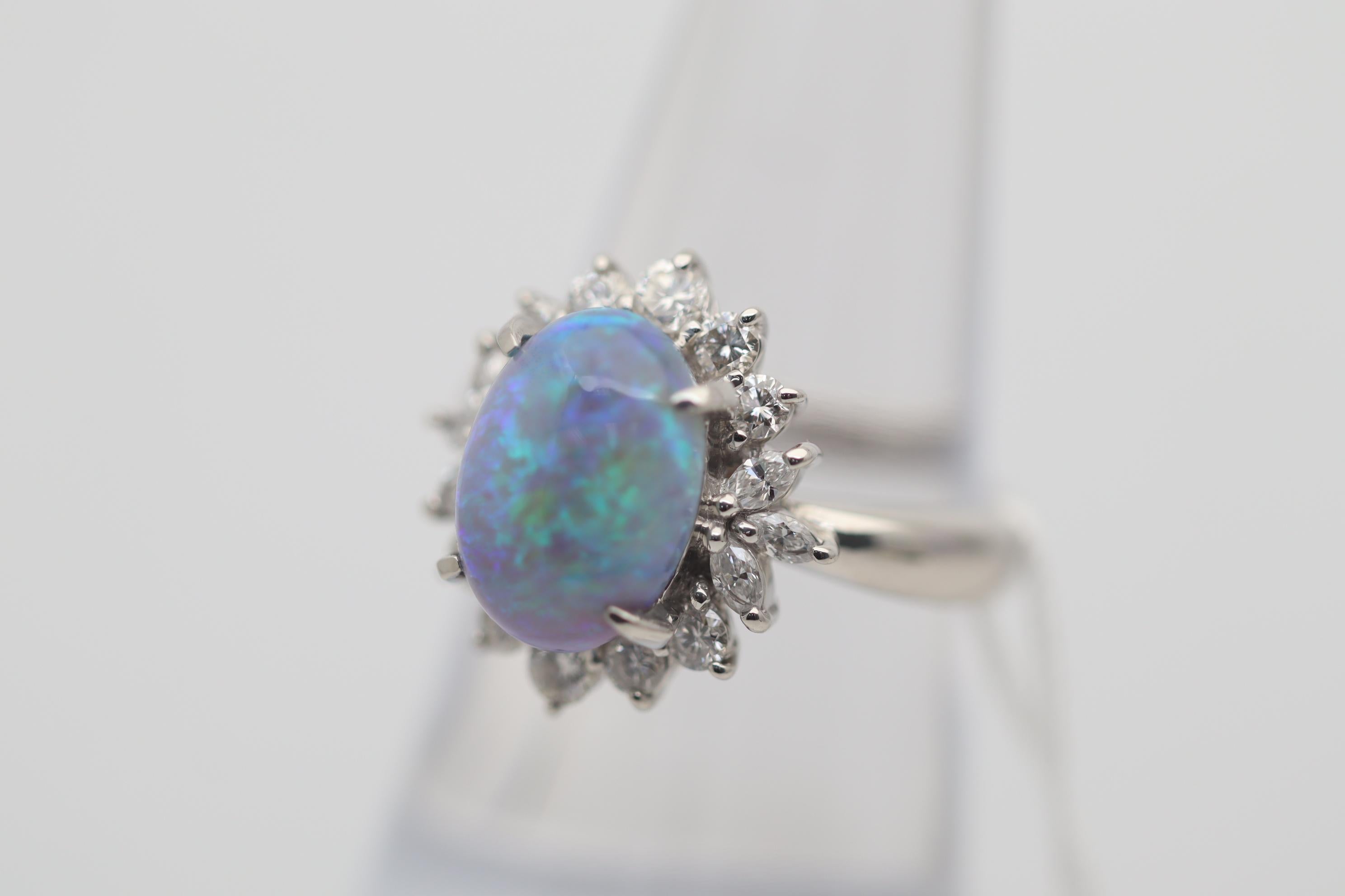 A lovely platinum ring featuring a 3.28 carat Australian crystal opal. It has great play of color as flashes of greens and blues dance across the stone. It is complemented by 0.77 carats of round-brilliant and marquise-shape diamonds set around the