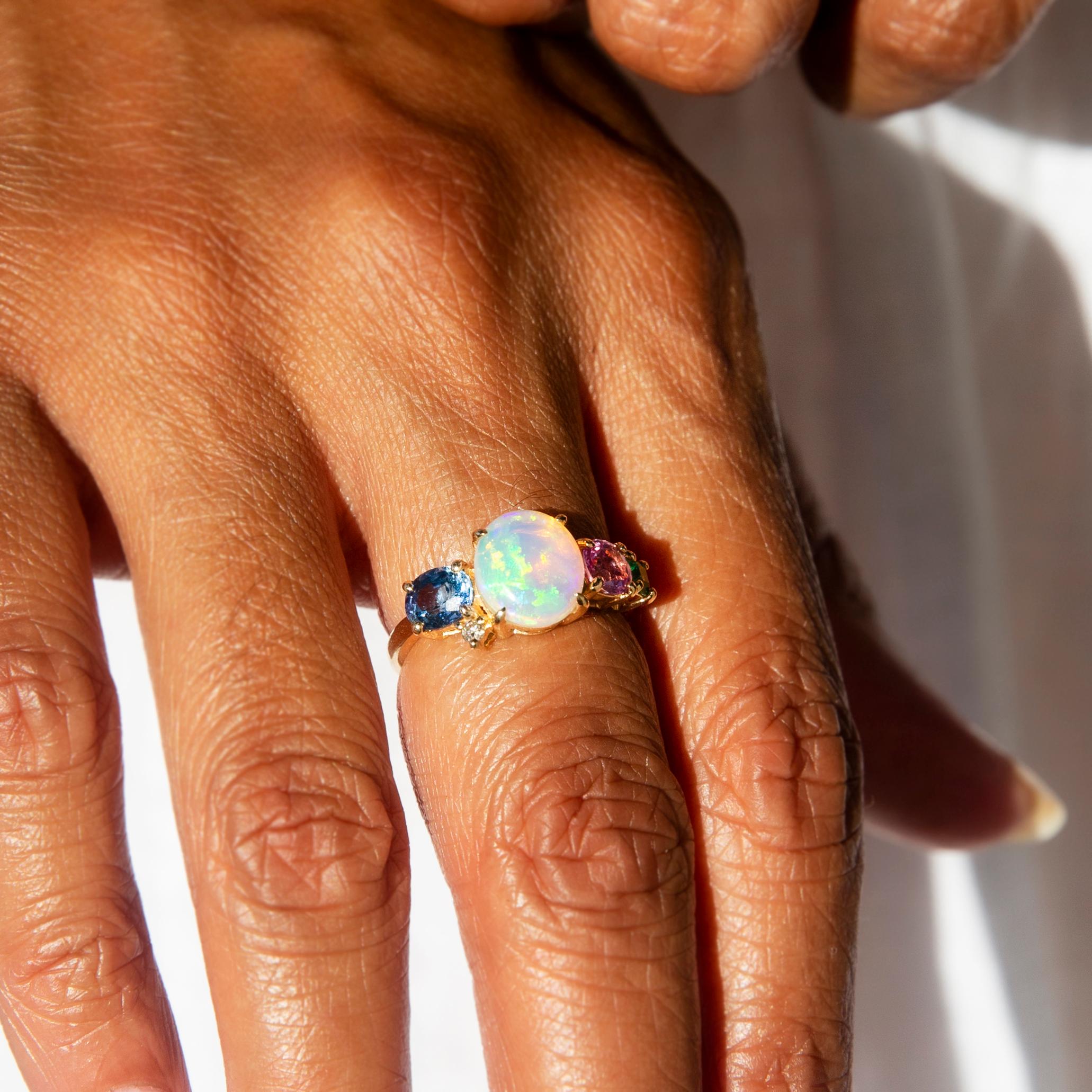 Crafted with love and devotion to craft, this gorgeous 18 carat gold contemporary wonder holds at her centre a delightful translucent Australian crystal opal teeming with flashes of green. To one side are an alluring bright blue Ceylon-type sapphire