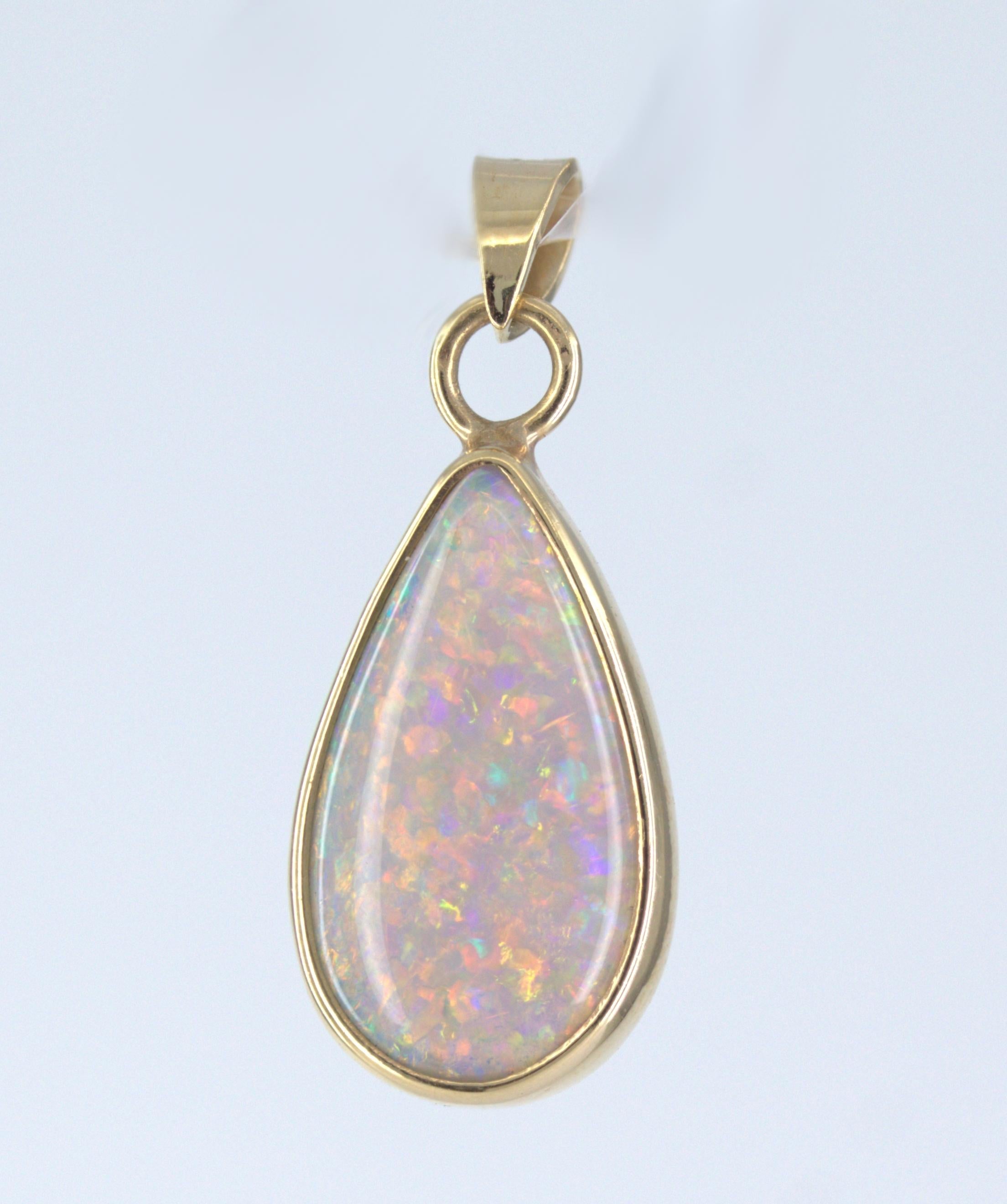 Featuring (1) beautiful pear-shaped grey crystal opal, with play of colors from red to orange and blue to green, in a floral harlequin pattern throughout, 15 X 8 X 3 mm, bezel set in a 14k yellow gold mounting, 22.4 X 9.7 X 3.3 mm, with articulated