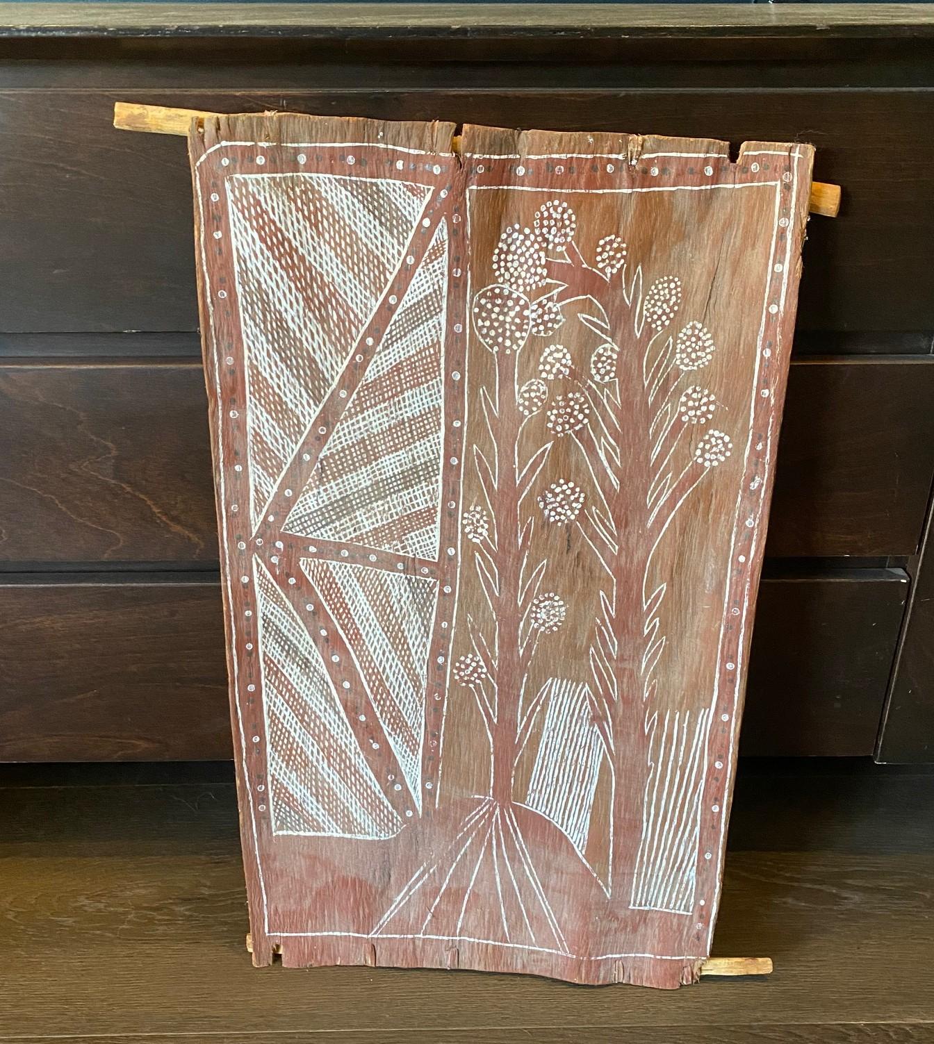 Une merveilleuse, unique et très attachante peinture aborigène australienne originale représentant un arbre à fleurs dans un paysage le long d'un sentier avec des motifs géométriques.  La peinture est réalisée avec des pigments de terre naturels qui