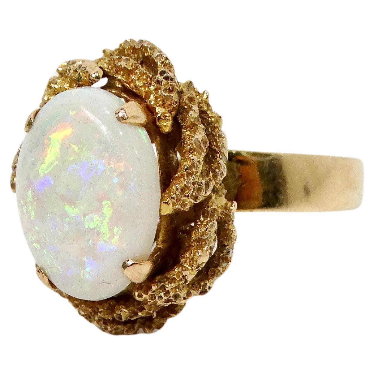 This stunning Australian Opal 18k Gold Cocktail Ring from the circa 1970s exemplifies vintage elegance and bold craftsmanship. The ring features a large, captivating opal with a mesmerizing play of vibrant colors—blues, greens, and fiery reds—that