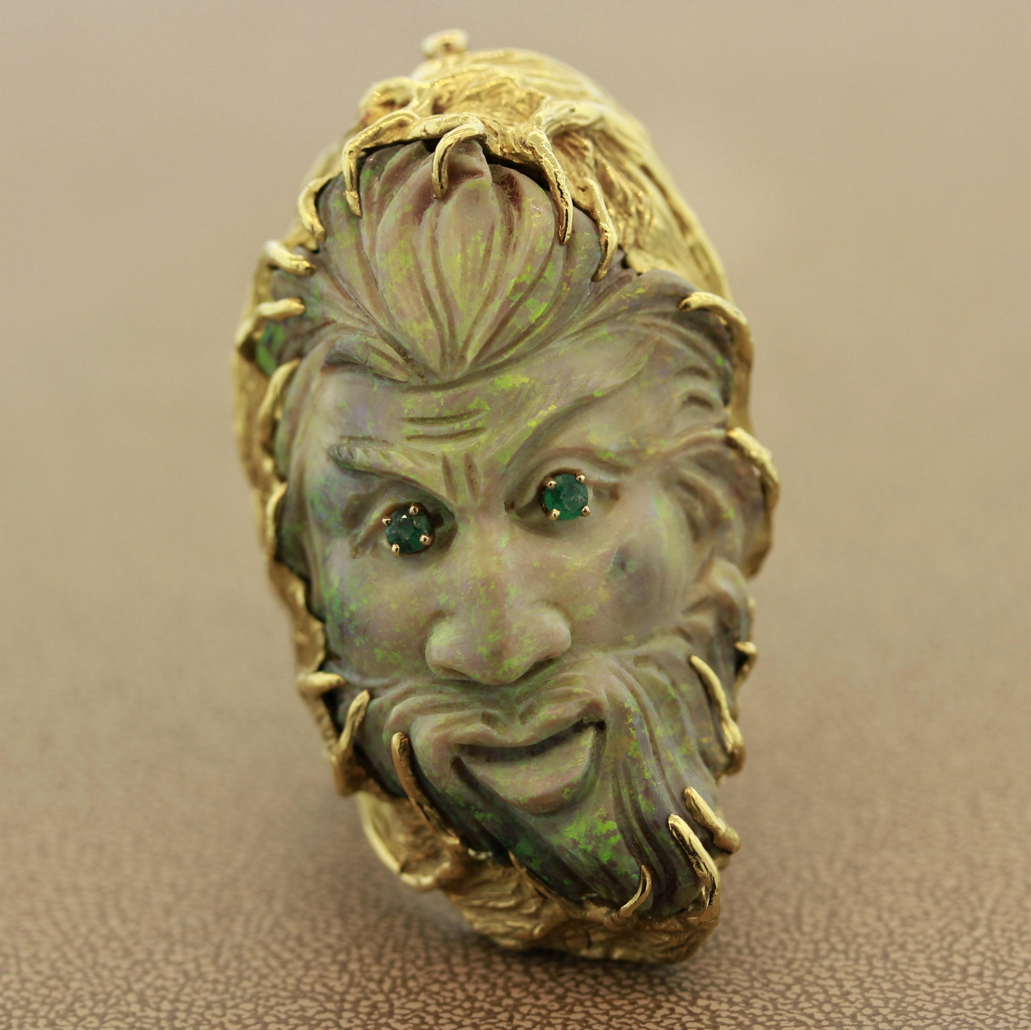 A true one of a kind collectors piece featuring a natural Australian opal hand carved The opal has great play of color showing flashes of green and orange across the stone. There are two emeralds that are set as the man's eyes. Hand fabricated in